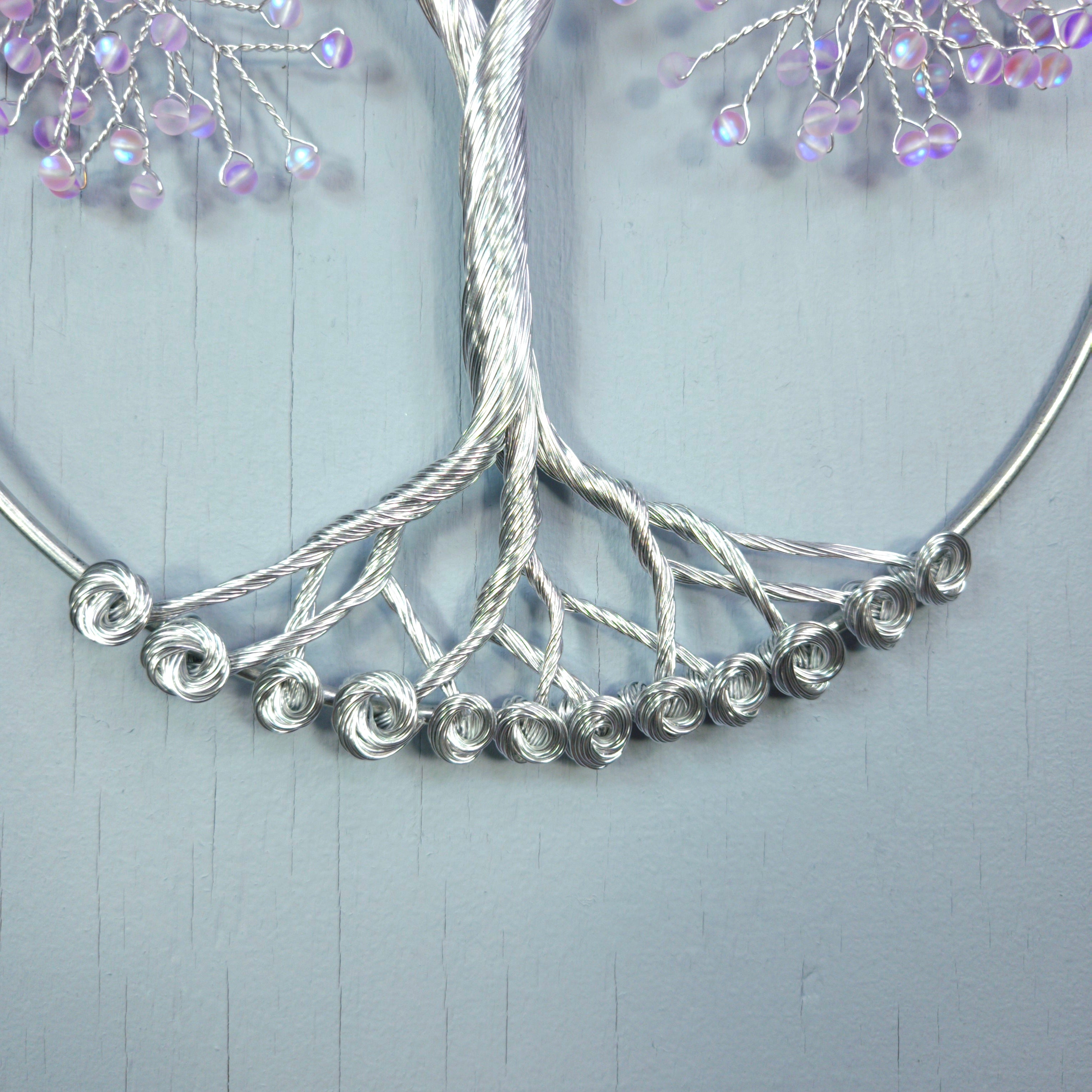Silver necklace with beaded branches on a light gray background