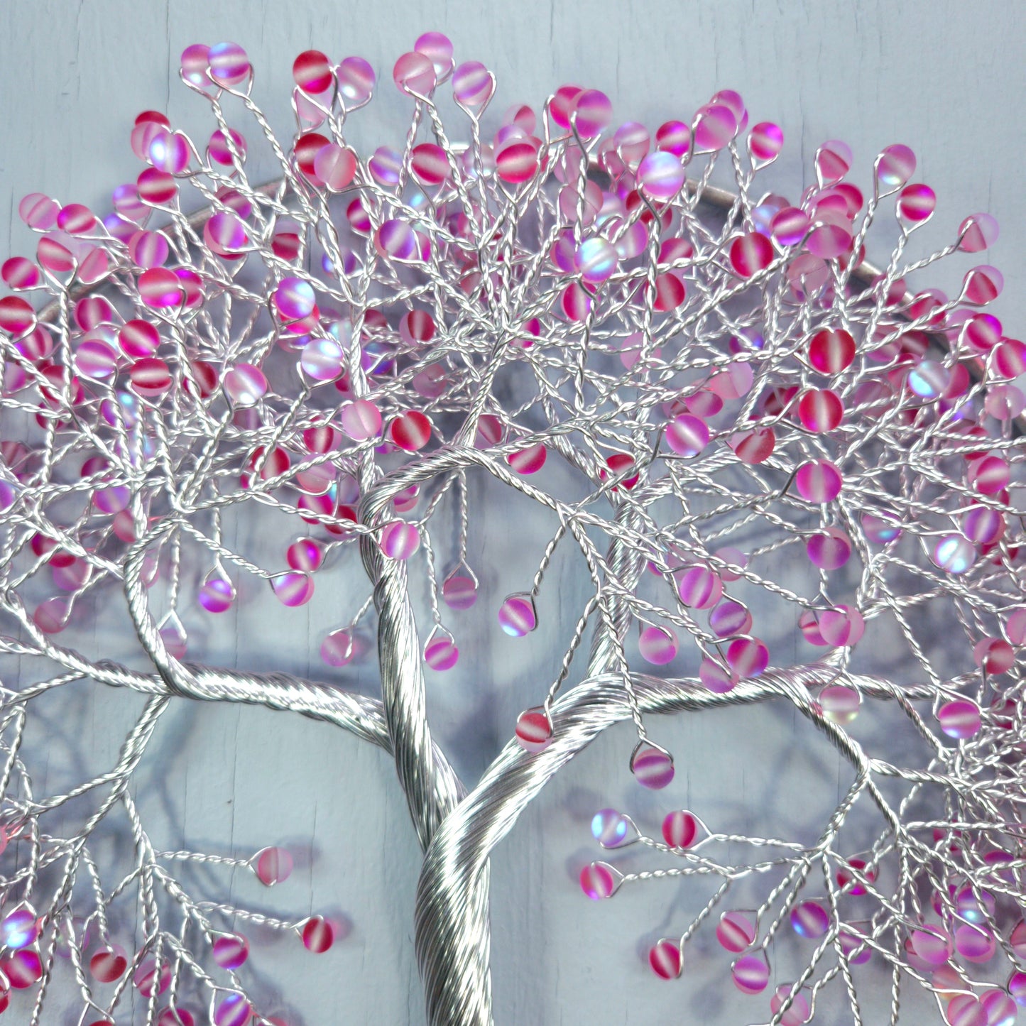 Decorative wall art of a tree with pink and silver branches on a light gray background