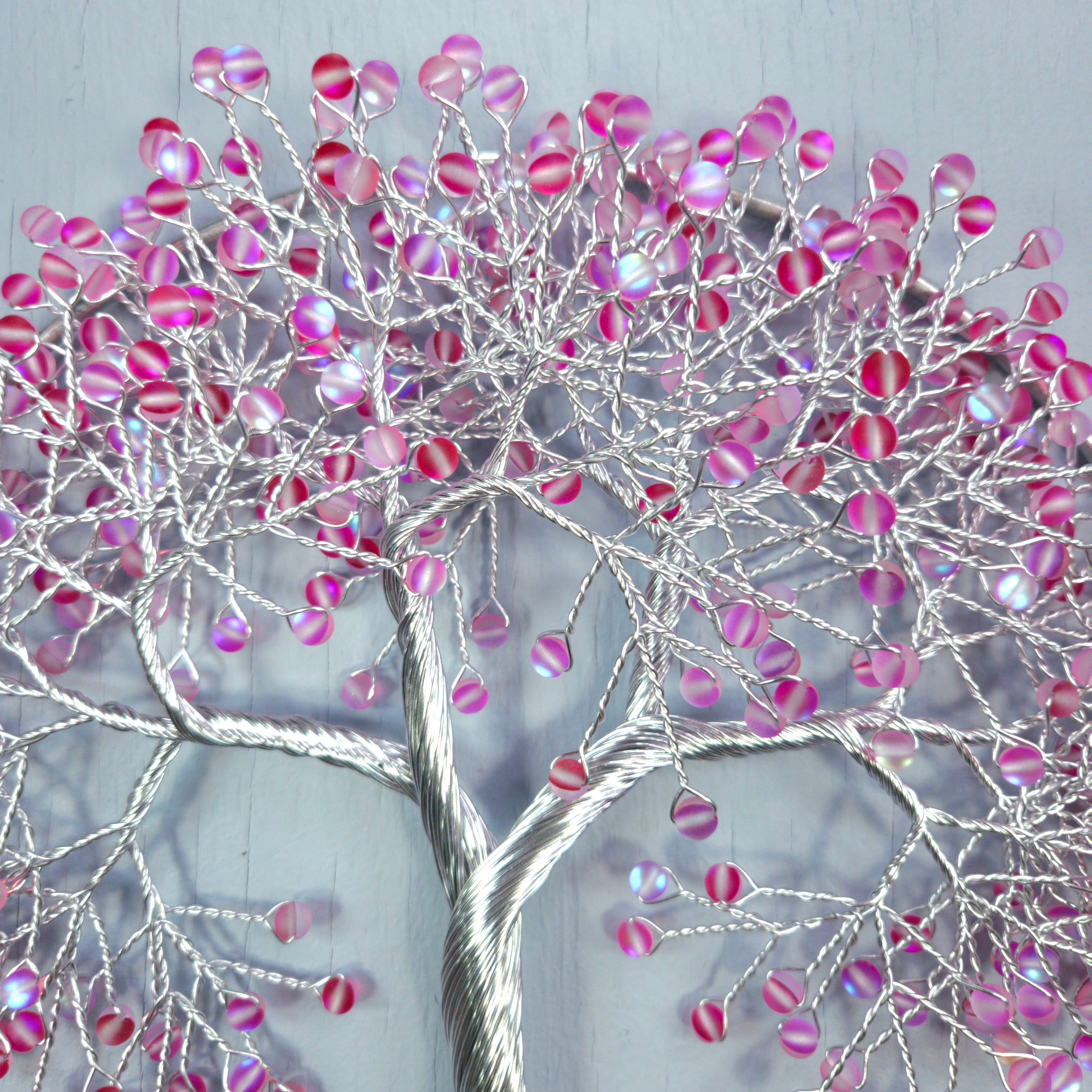 Decorative wall art of a tree with pink and silver branches on a light gray background