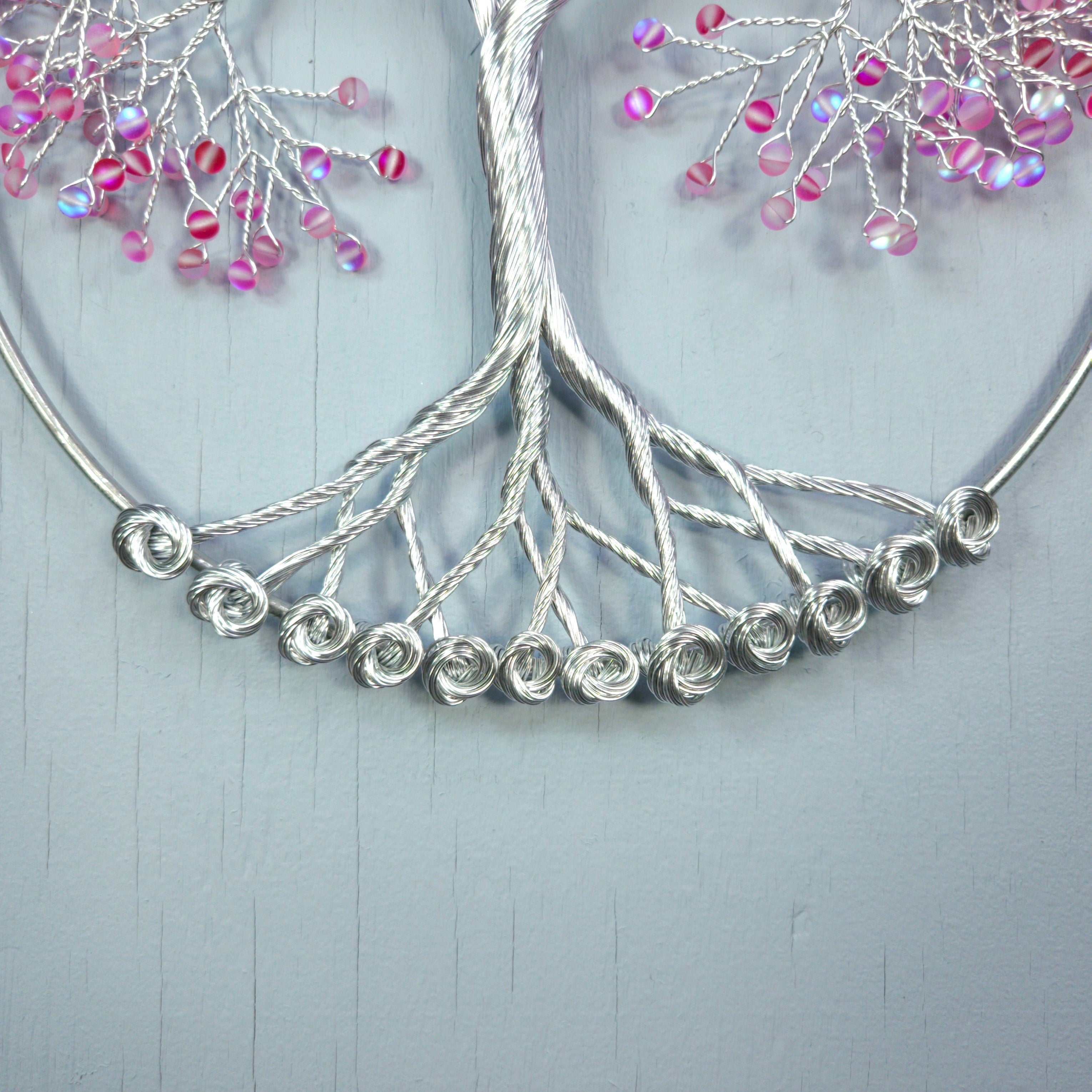 Silver jewelry with pink beads on a light gray background