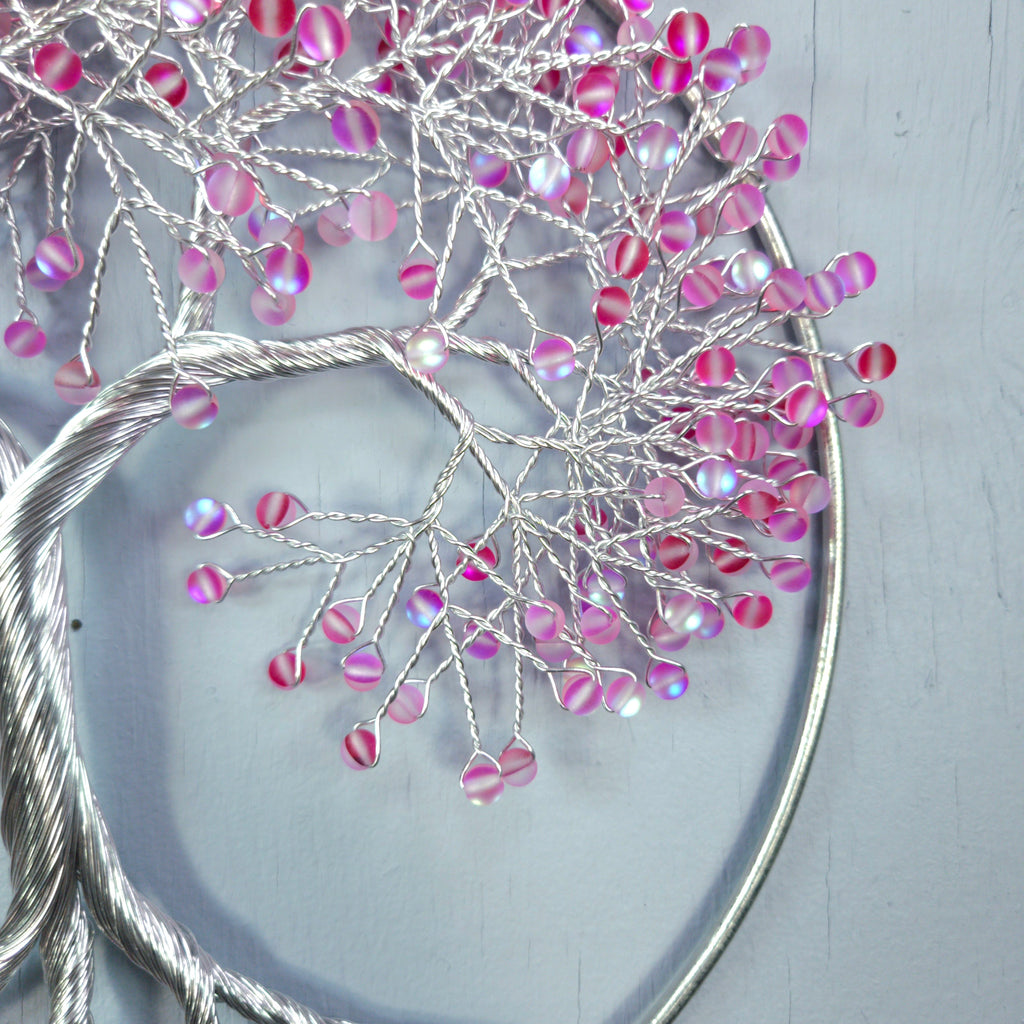 Decorative branch with pink and purple beads on a light gray background