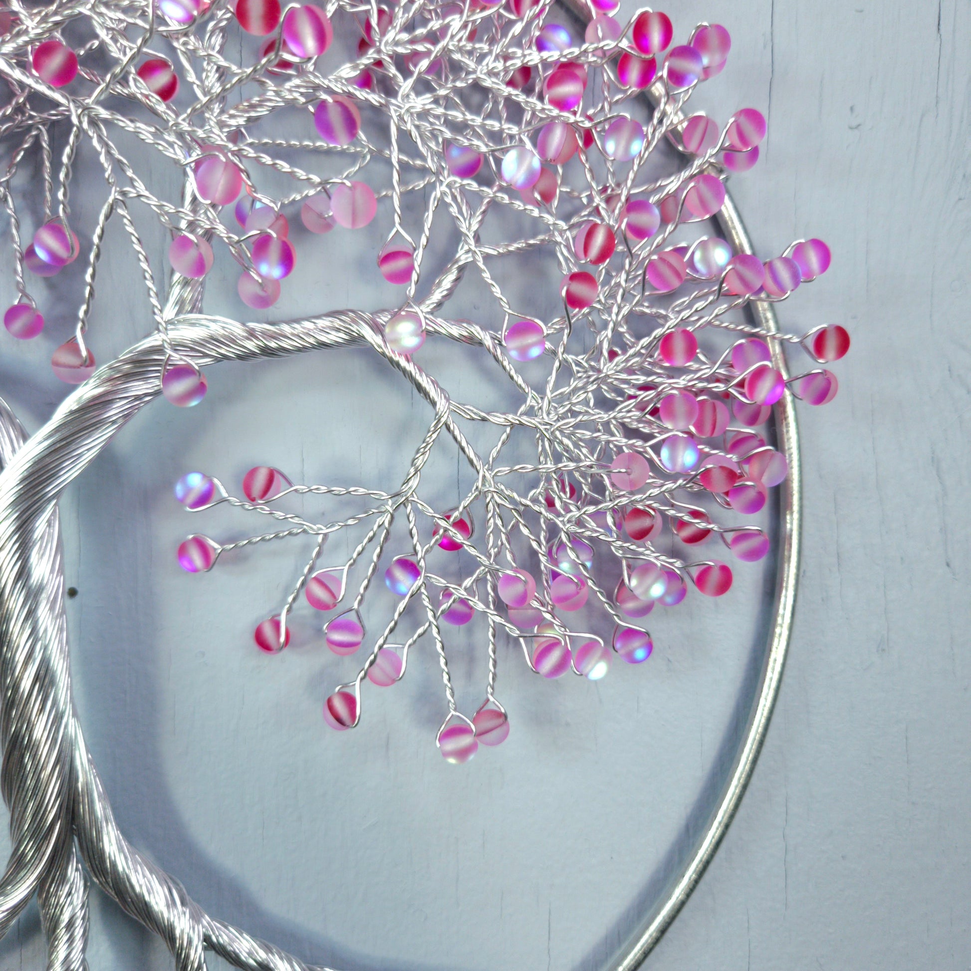 Decorative branch with pink and purple beads on a light gray background