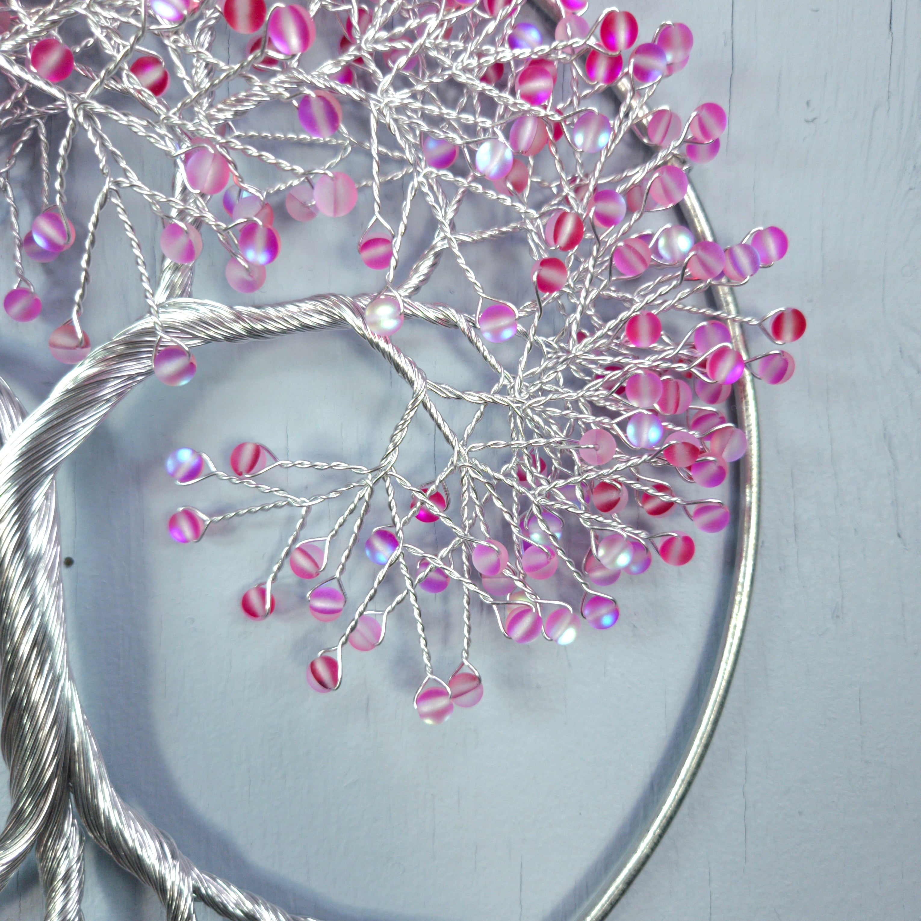 Decorative branch with pink and purple beads on a light gray background