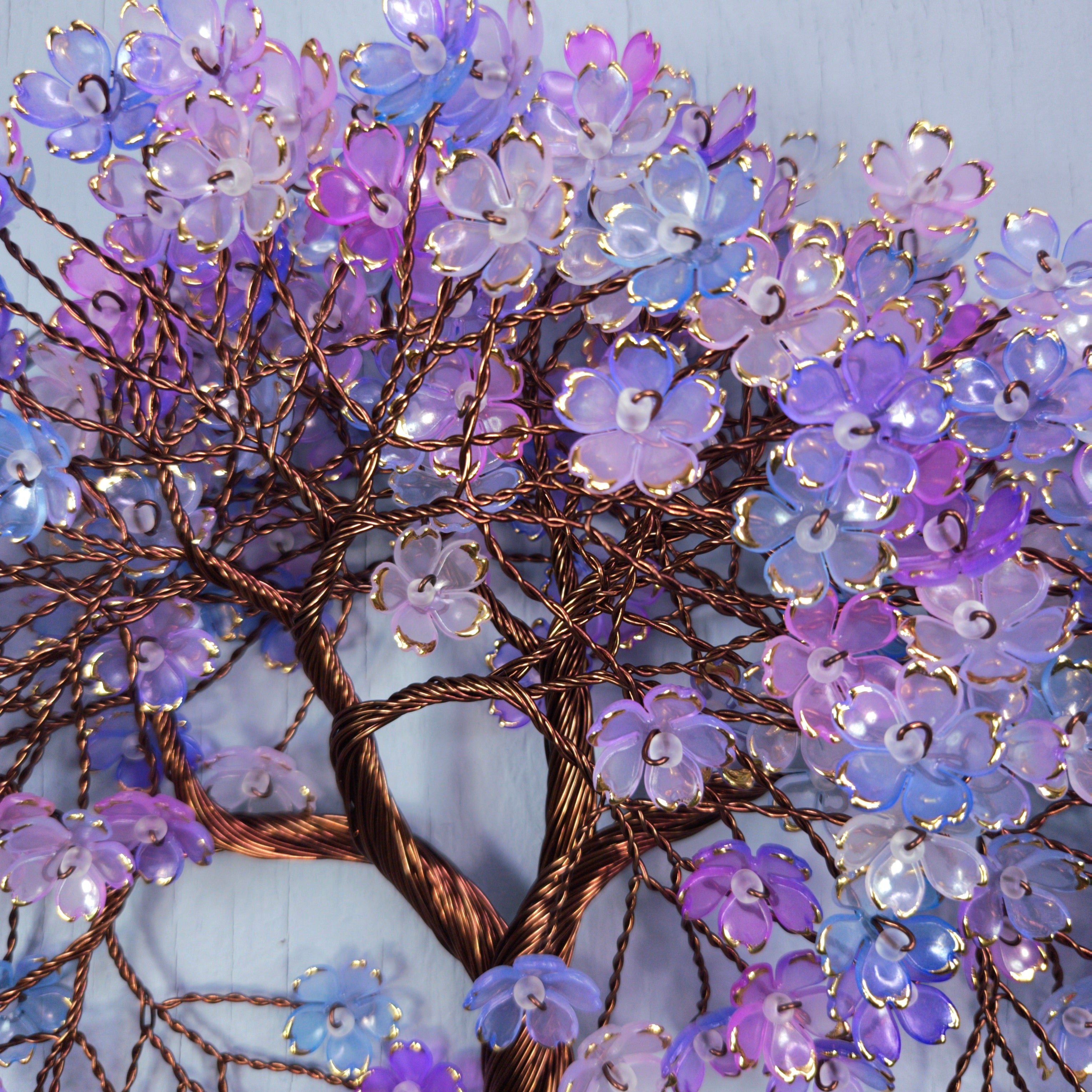 Decorative wall art of a tree with purple and blue flowers on a light blue background