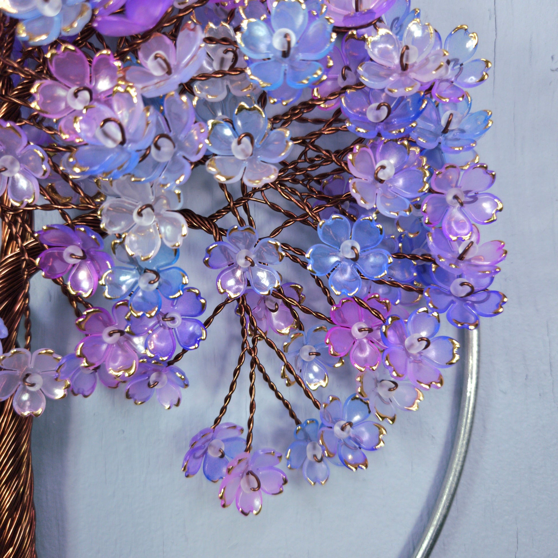 Close-up of a decorative brooch with purple and blue floral design on a light blue background