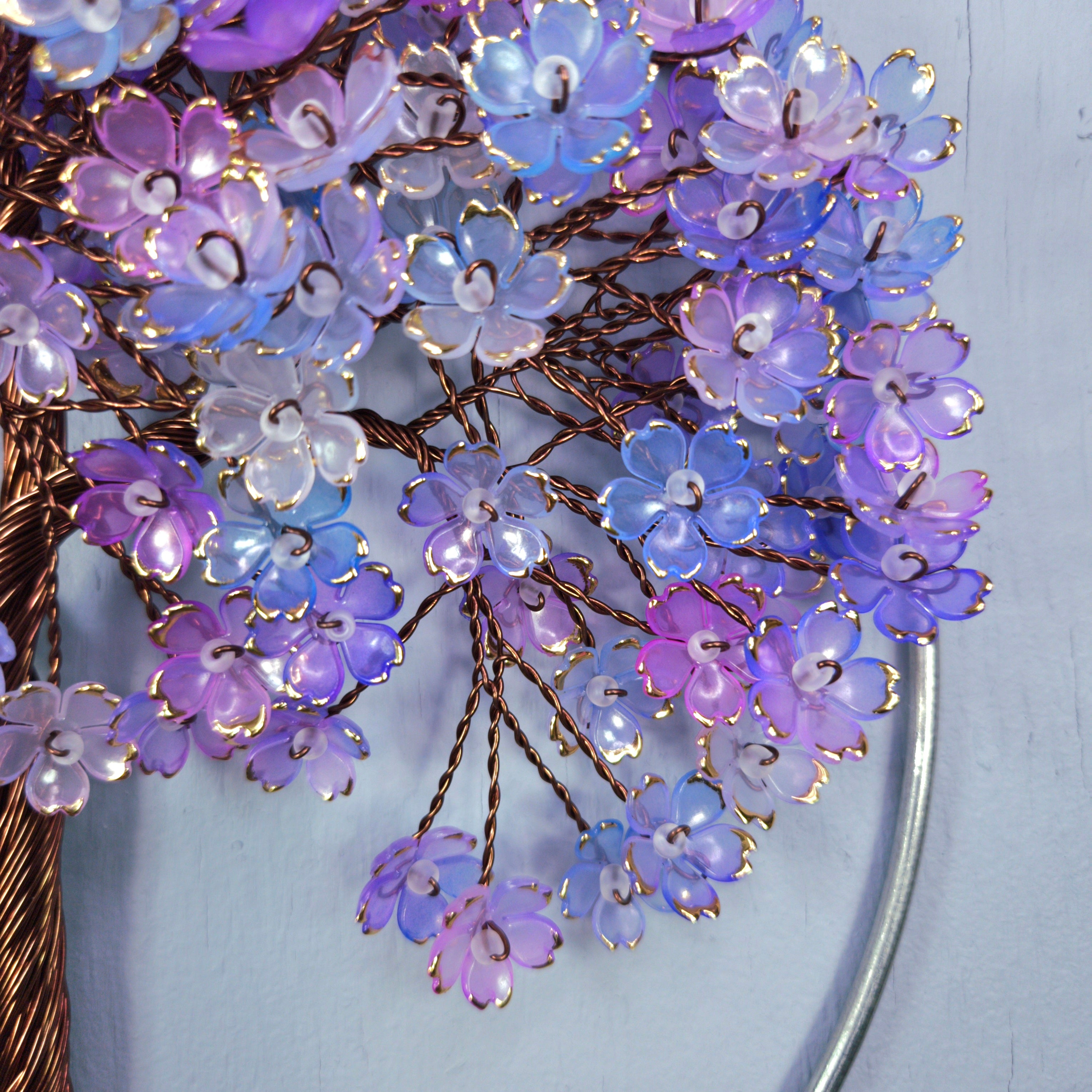 Close-up of a decorative brooch with purple and blue floral design on a light blue background