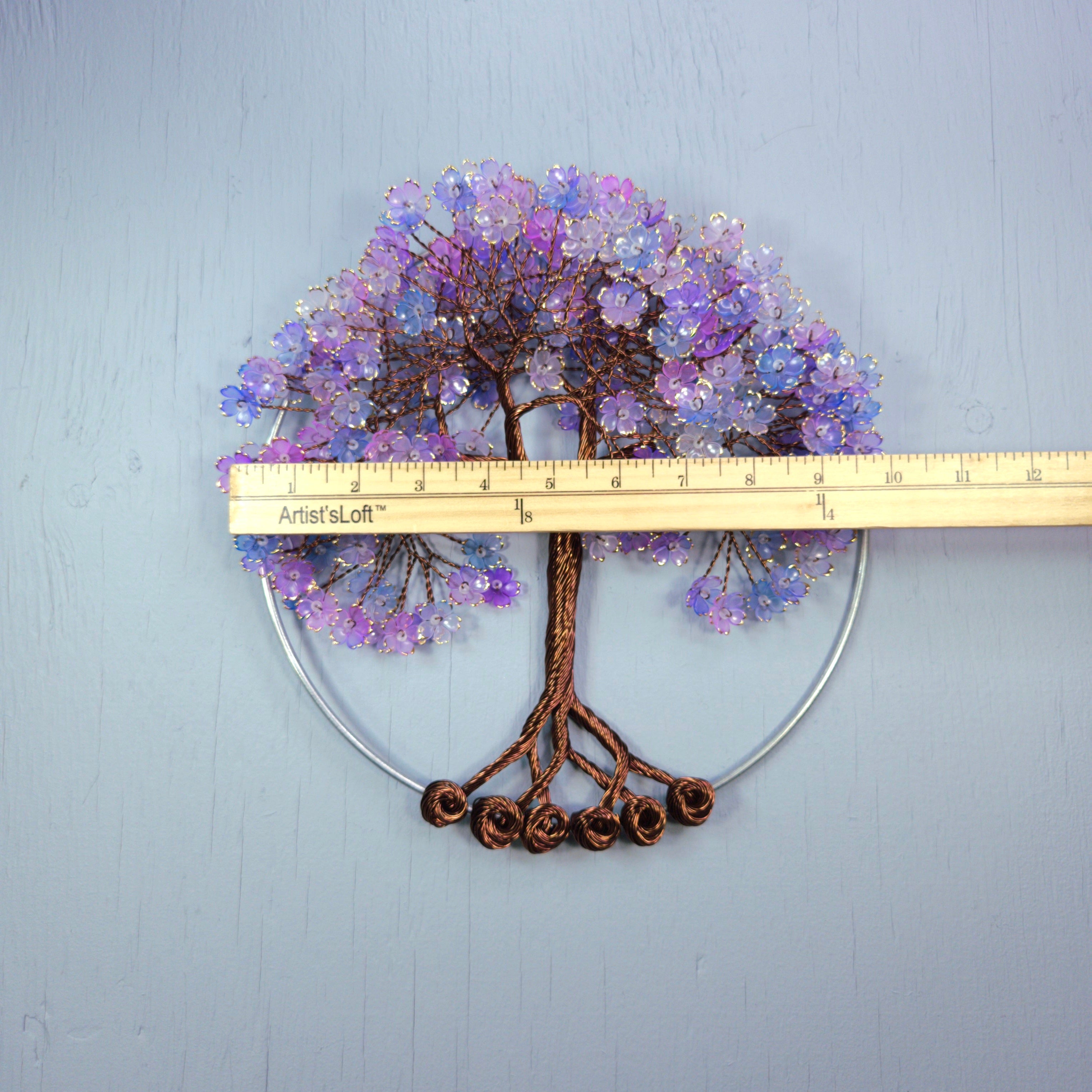 Decorative tree wall art with purple flowers and brown trunk, measured against a ruler on a light blue background.