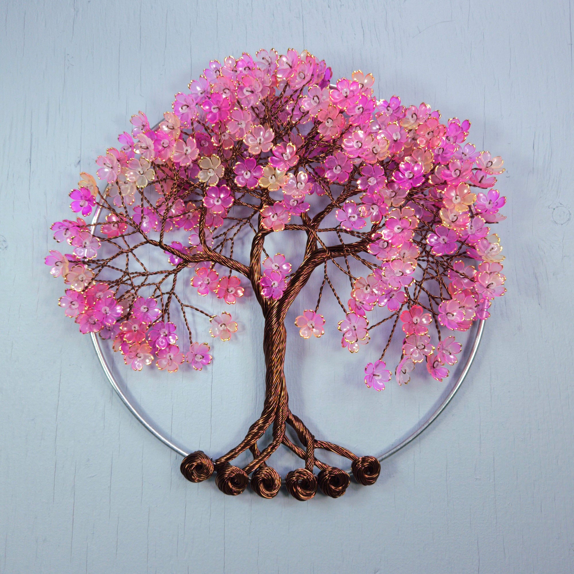 Decorative wall art of a tree with pink blossoms on a light blue background