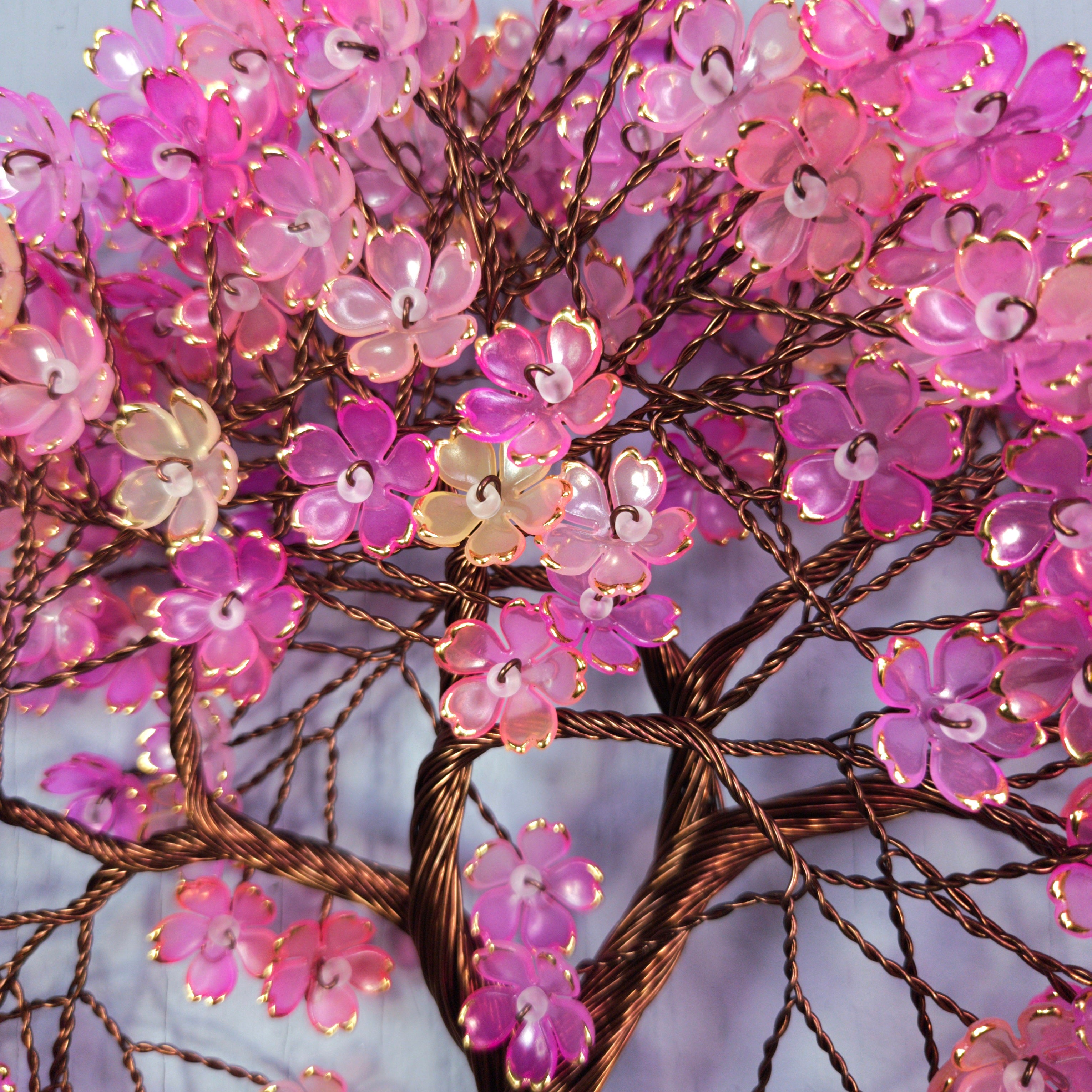 Decorative tree with pink and gold flowers against a light blue background