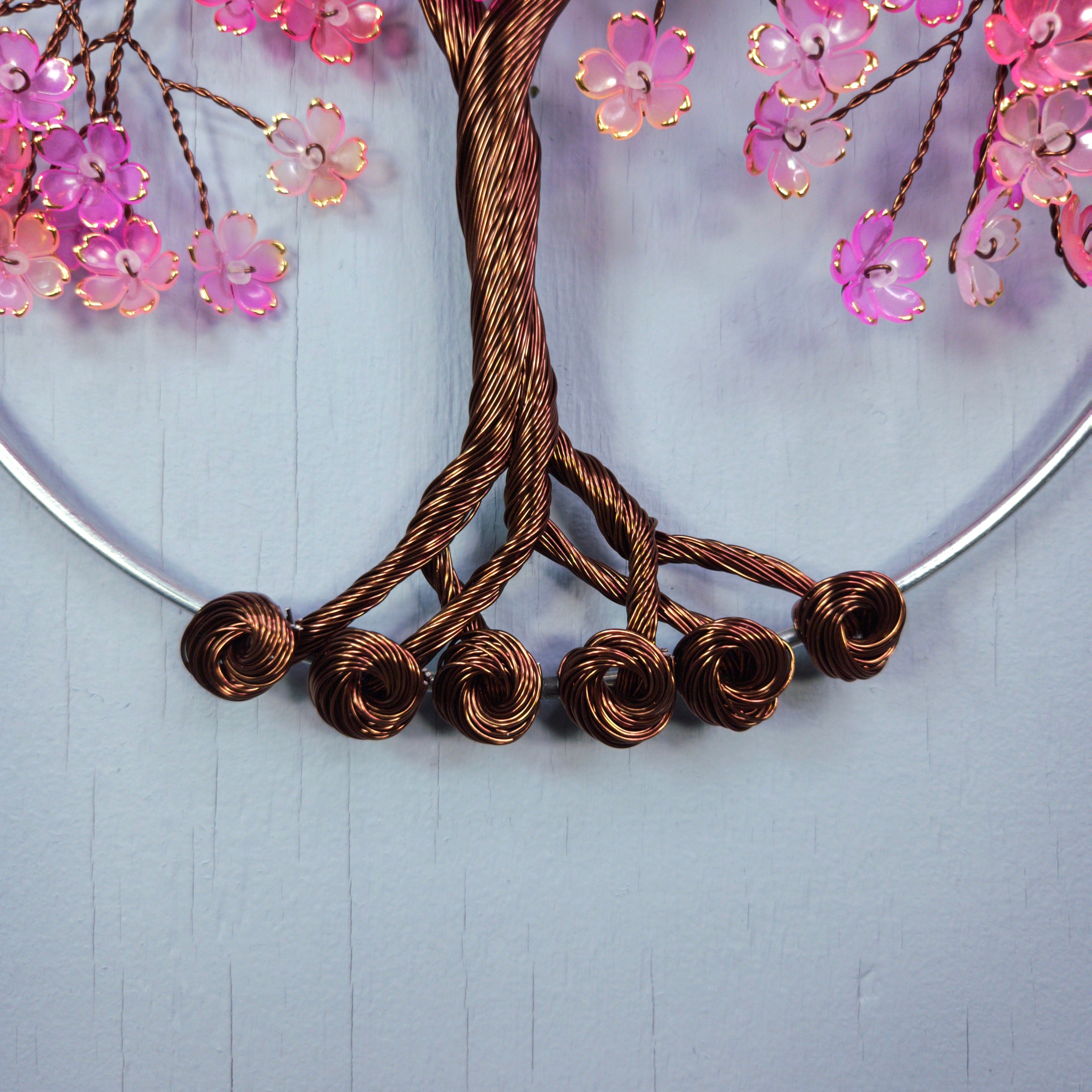 Decorative wreath with brown wire branches and pink flowers on a light blue background