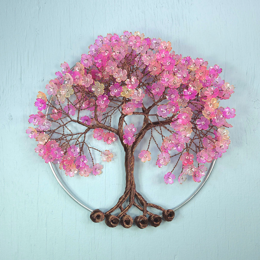 Decorative wall art of a tree with pink flowers on a light blue background