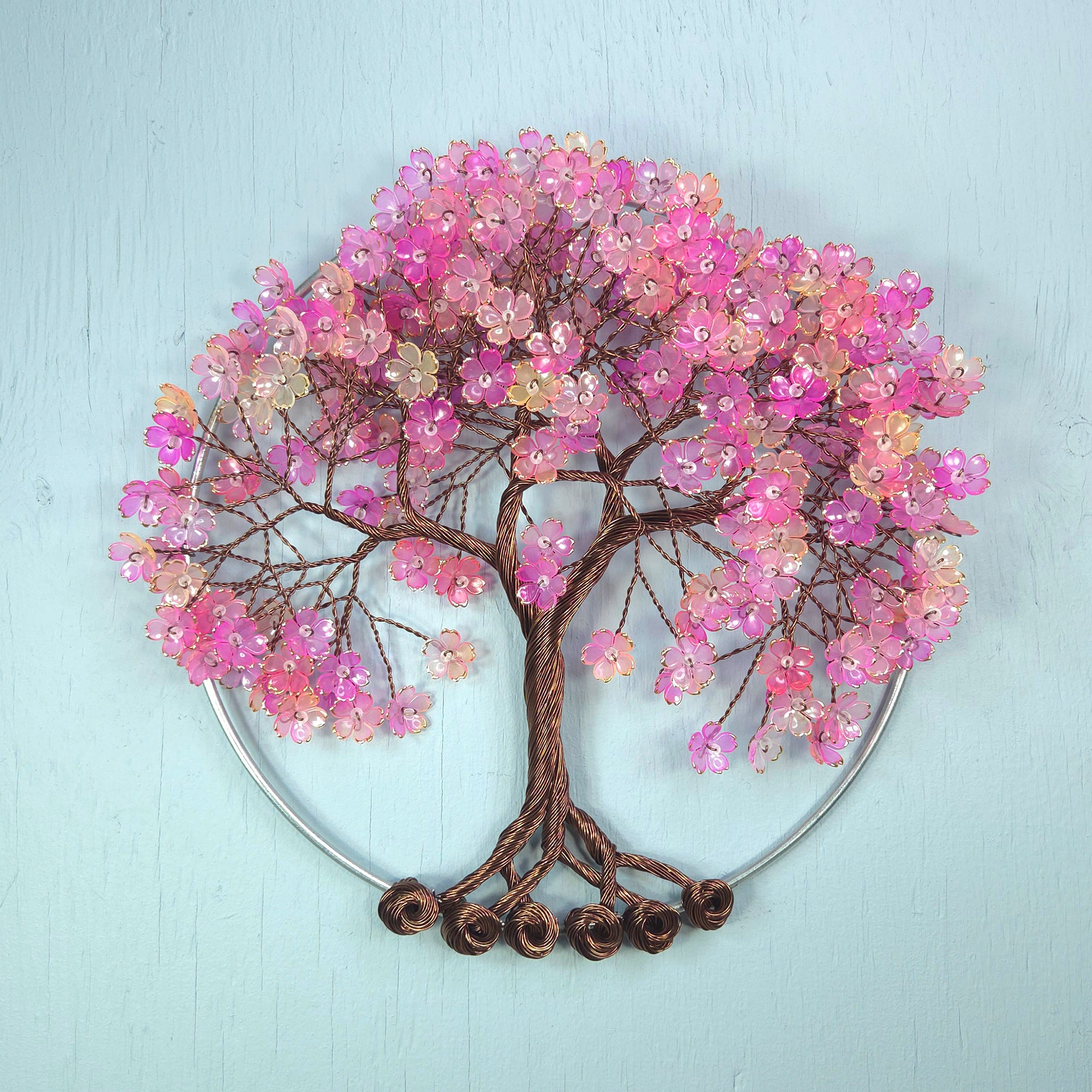 Decorative wall art of a tree with pink flowers on a light blue background