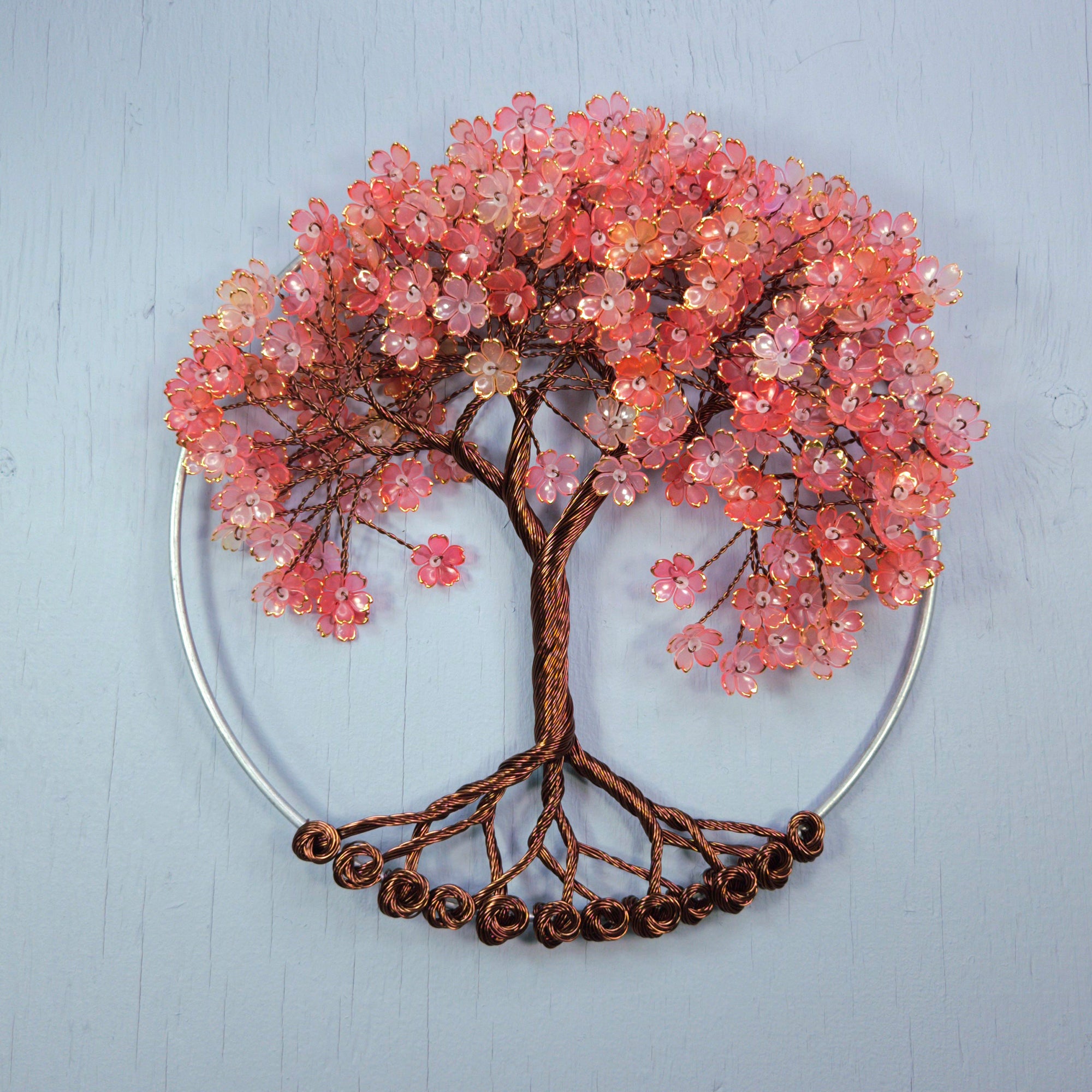 Decorative wall art of a tree with pink blossoms on a light blue background