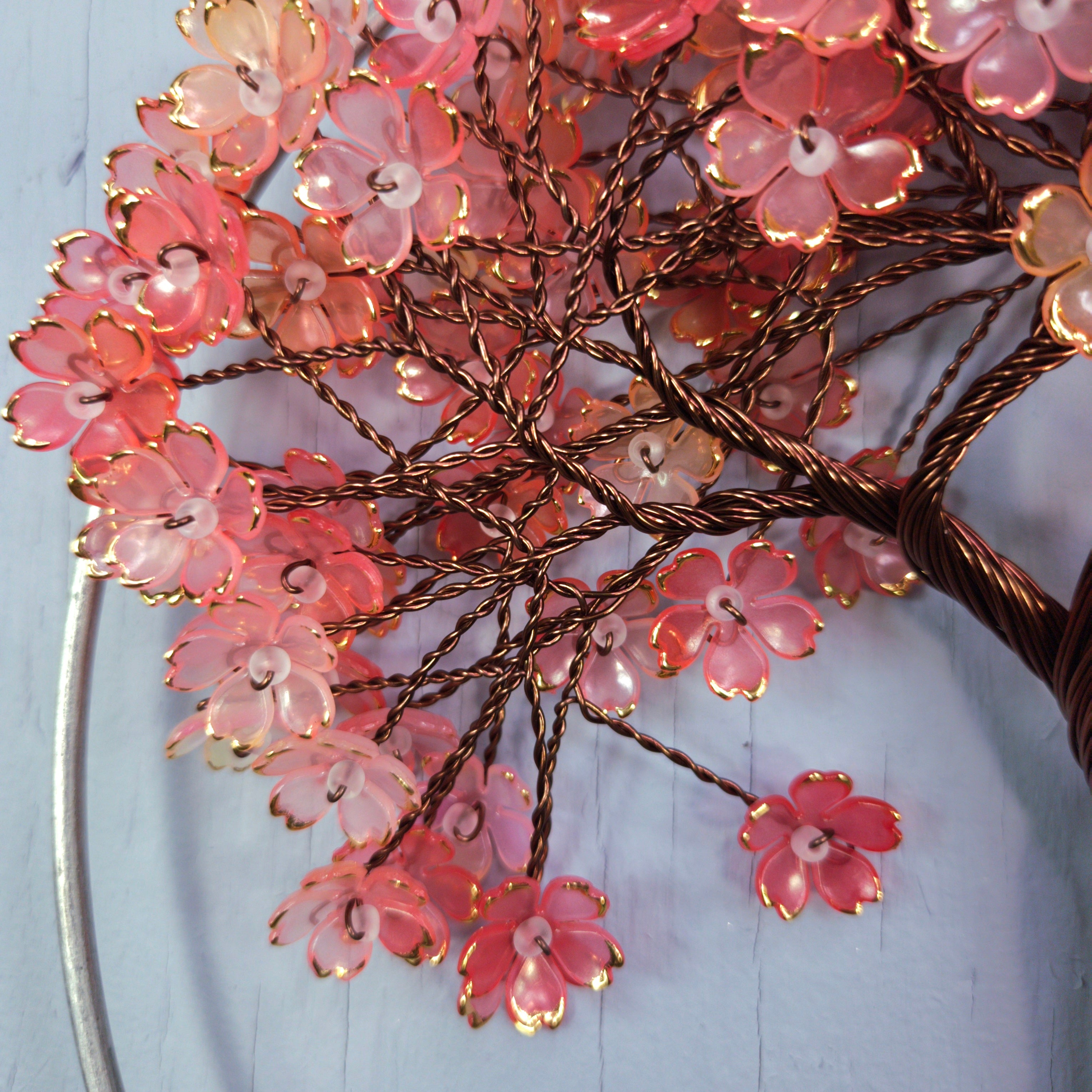 Decorative floral branch with pink flowers and gold accents on a light blue background