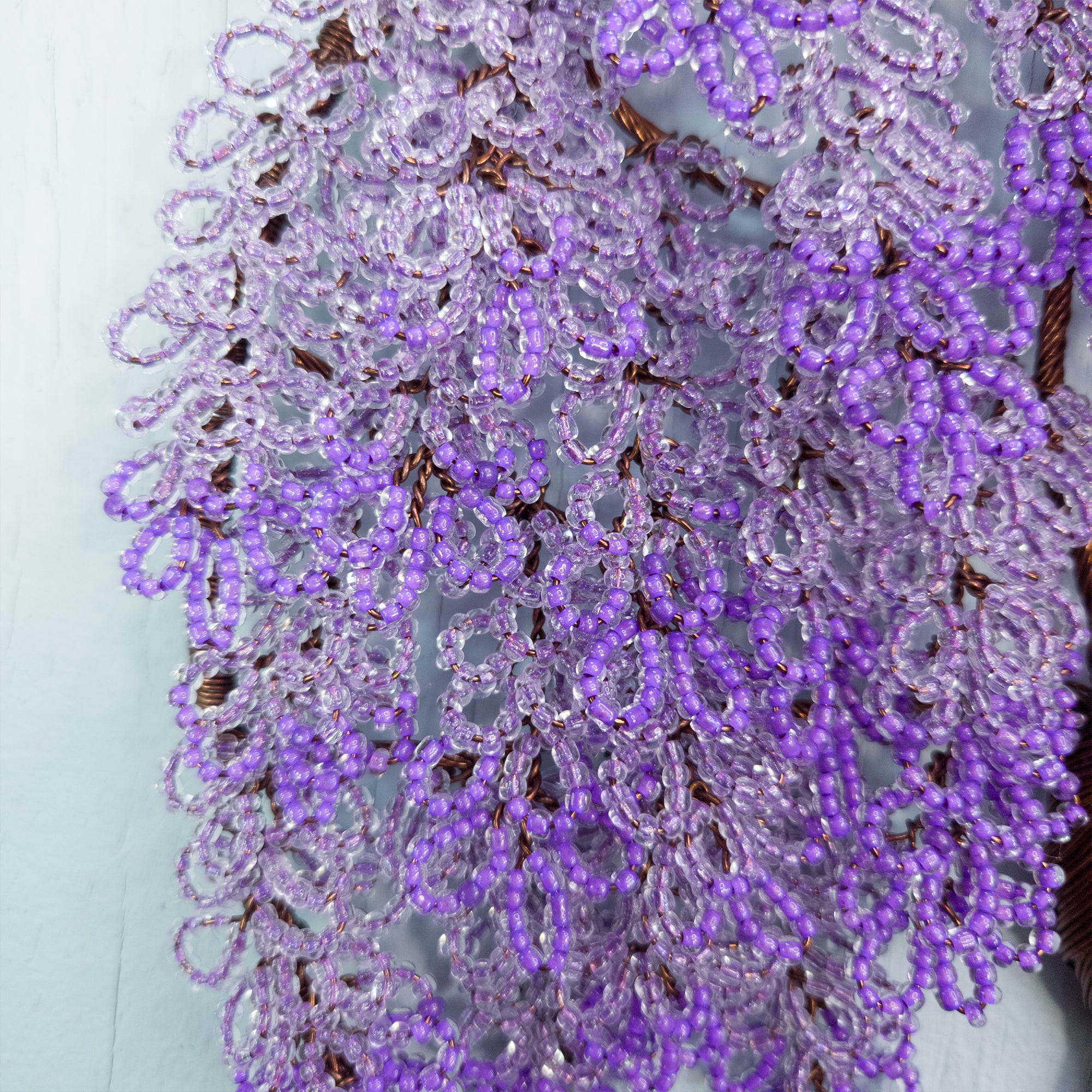 Close-up of a purple beaded wreath against a light background