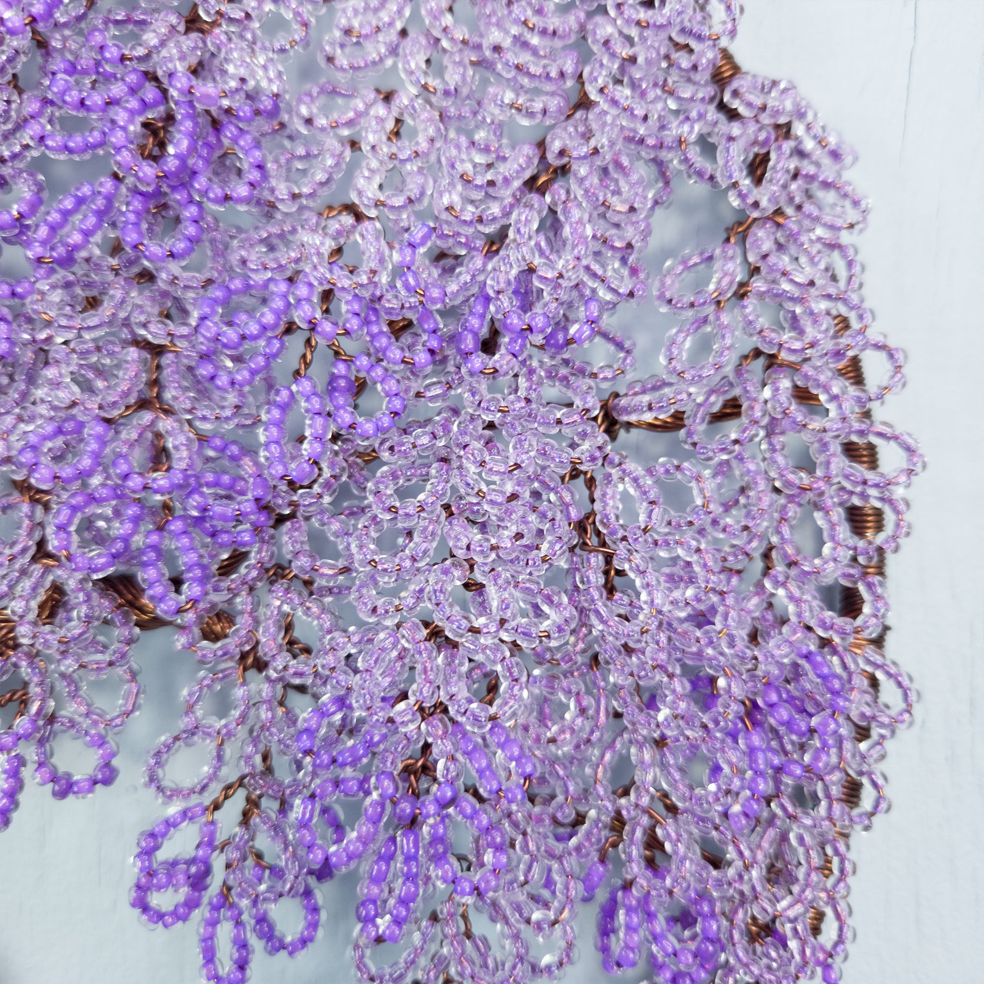 Close-up of a purple beaded scarf on a light gray background