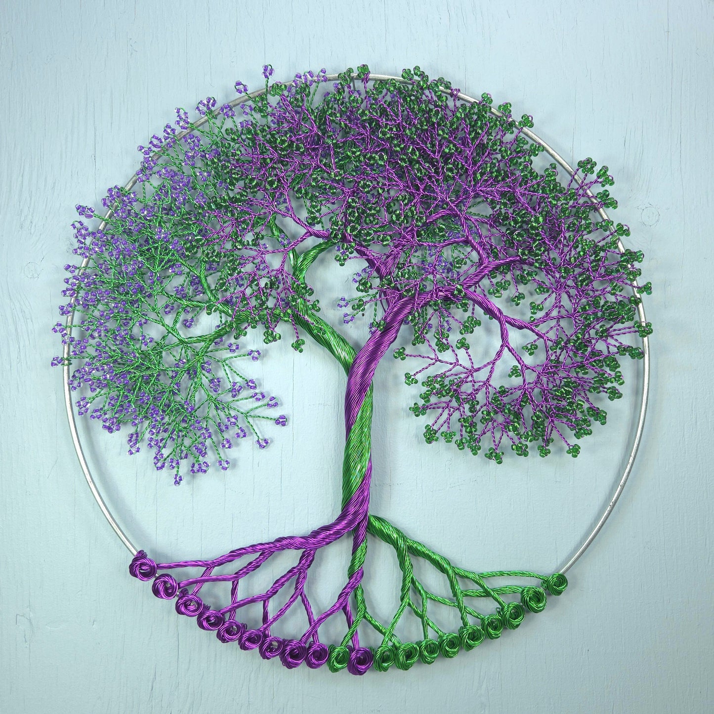 Decorative wall art of a tree with purple and green branches on a light blue background