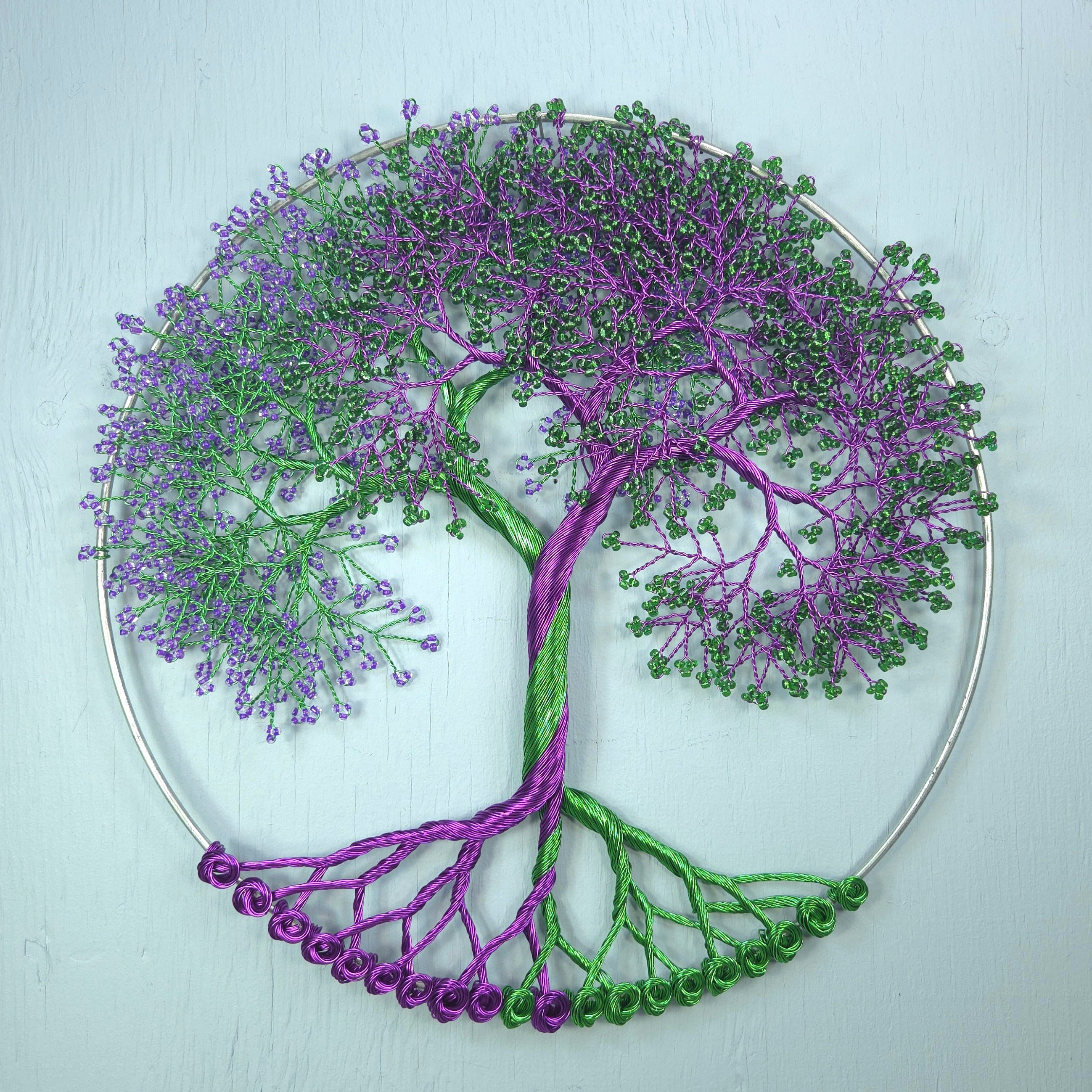 Decorative wall art of a tree with purple and green branches on a light blue background