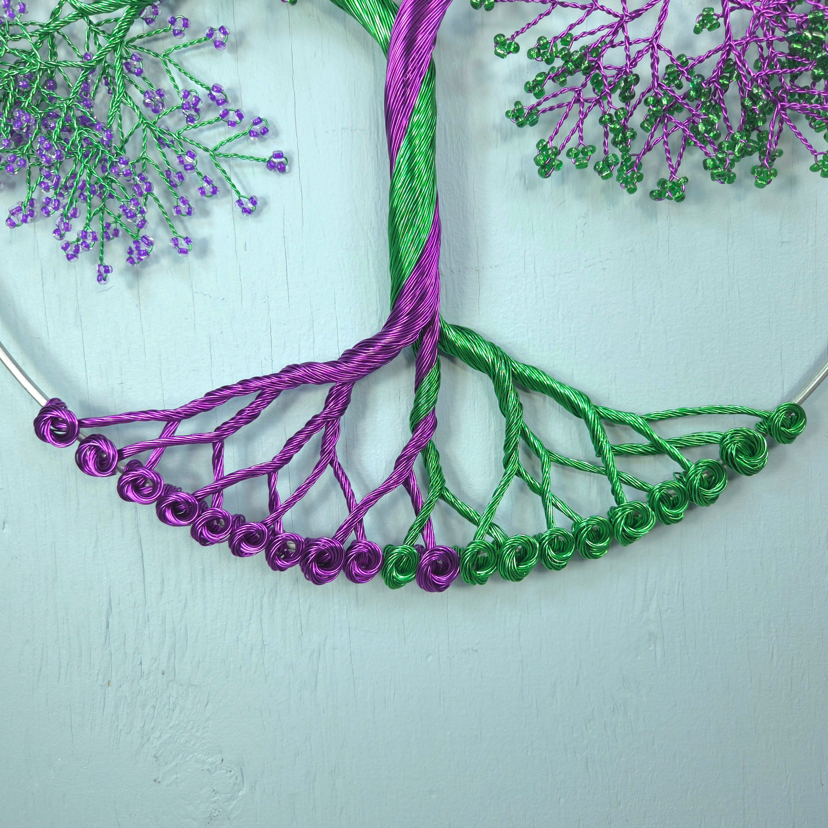 Embroidery of a tree with purple and green threads on a light background