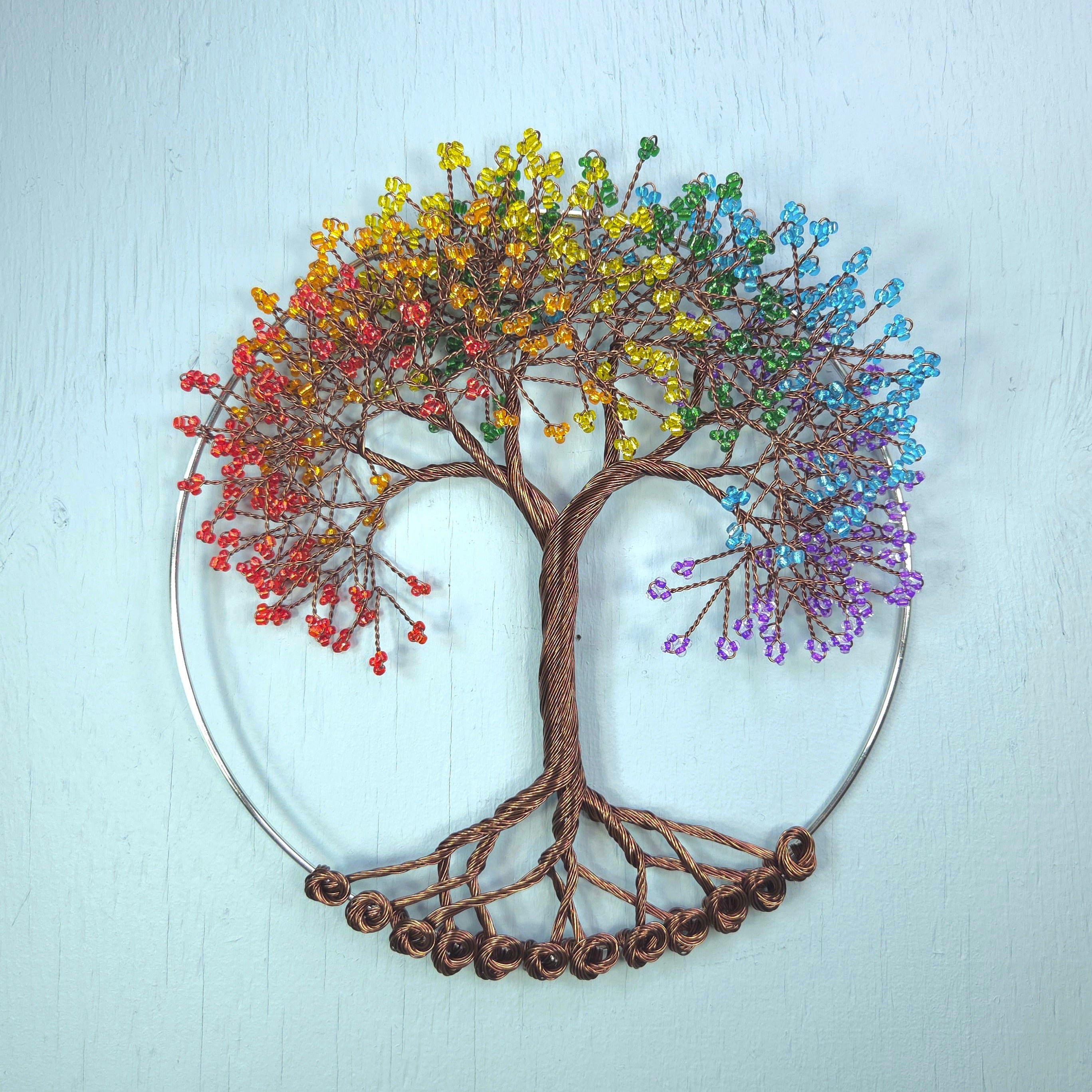 Decorative wall art of a tree with colorful beads on a light blue background