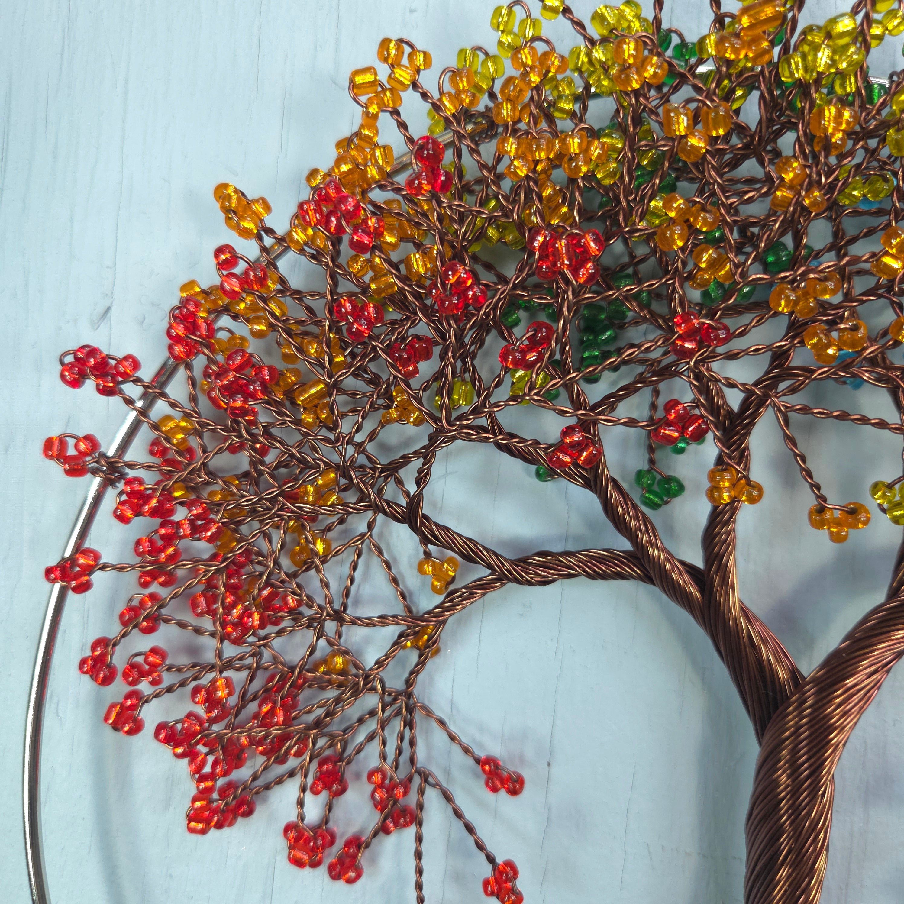 Decorative tree sculpture with colorful beads on a light blue background