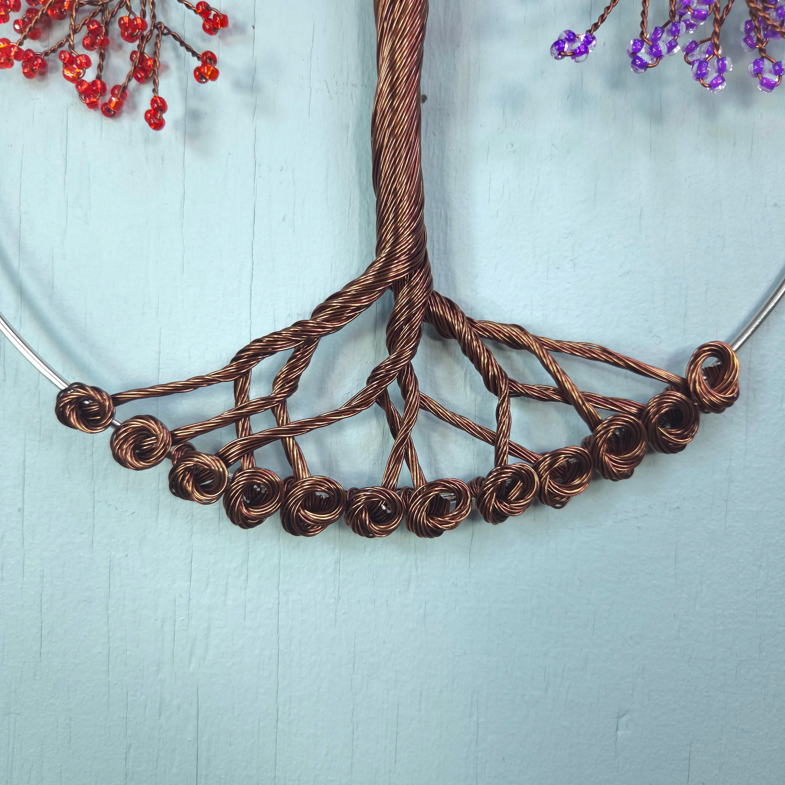 Close-up of a copper wire tree branch with small flowers on a light blue background