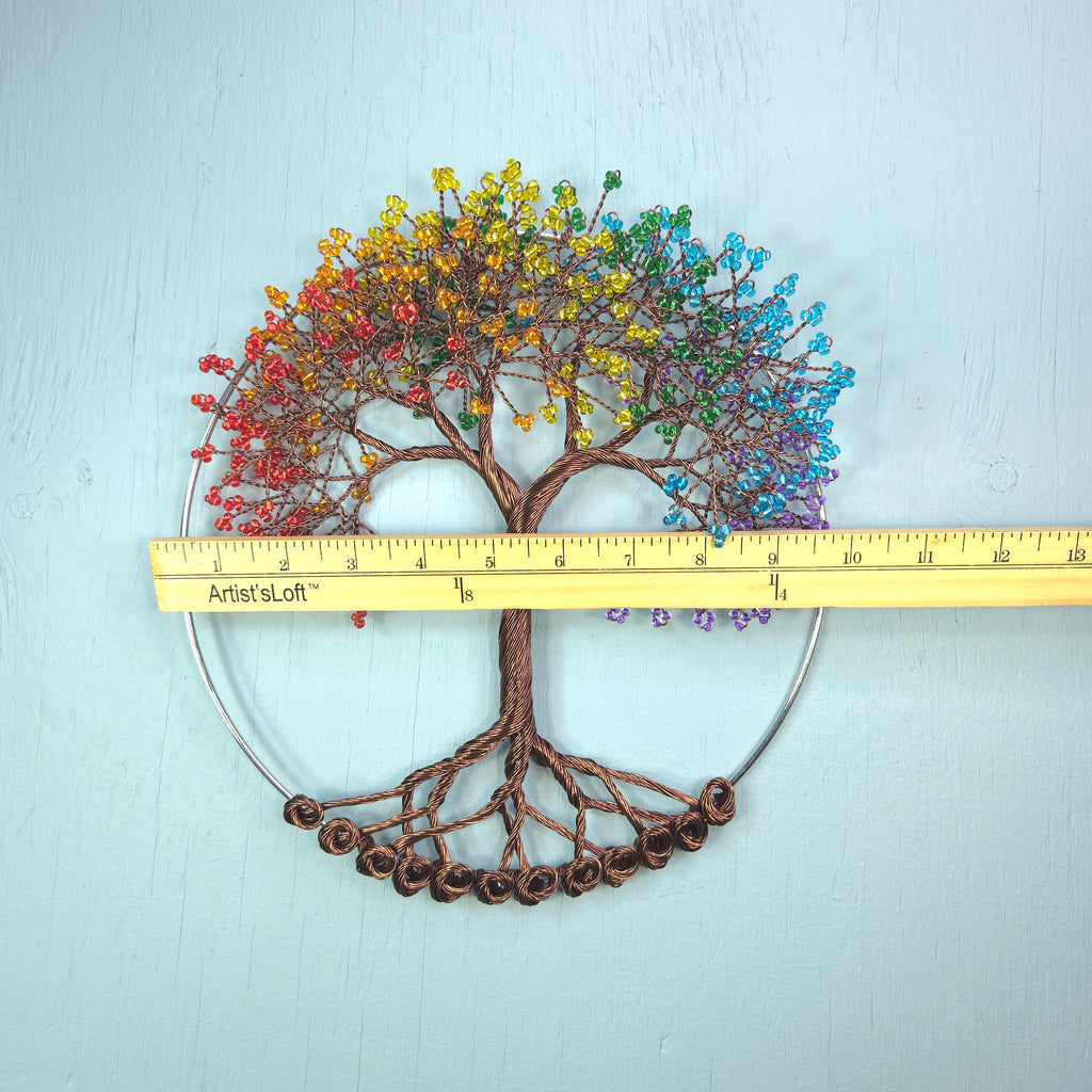 Decorative tree wall art with colorful leaves and a ruler for scale on a light blue background