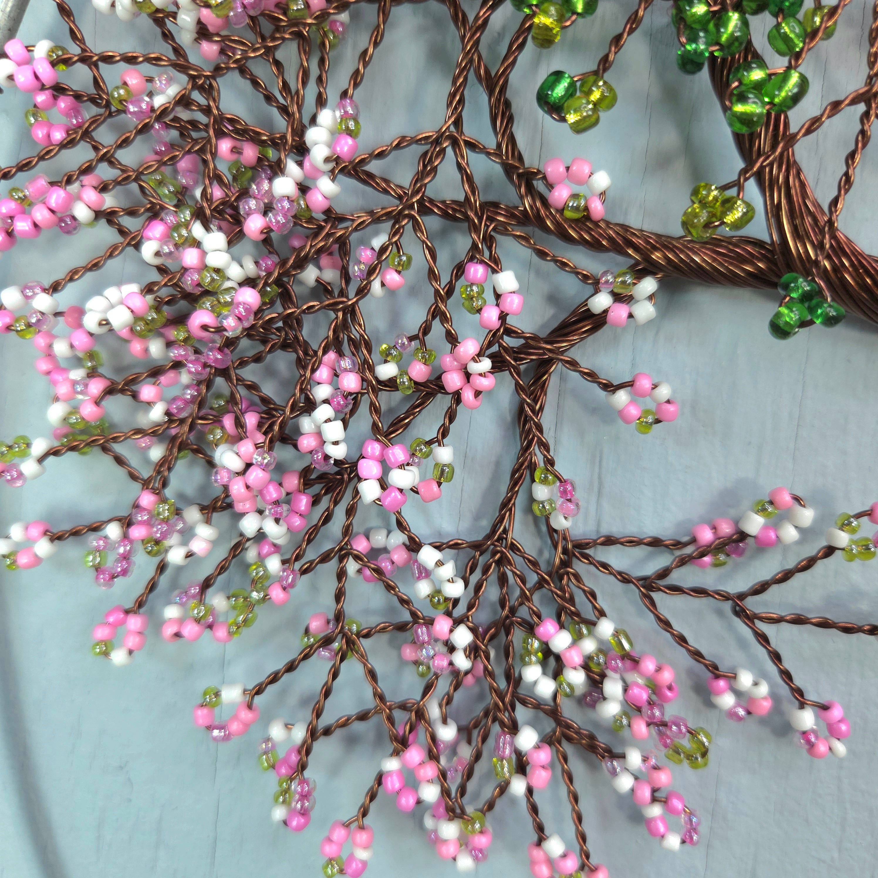 Decorative wall art with beaded branches on a textured surface
