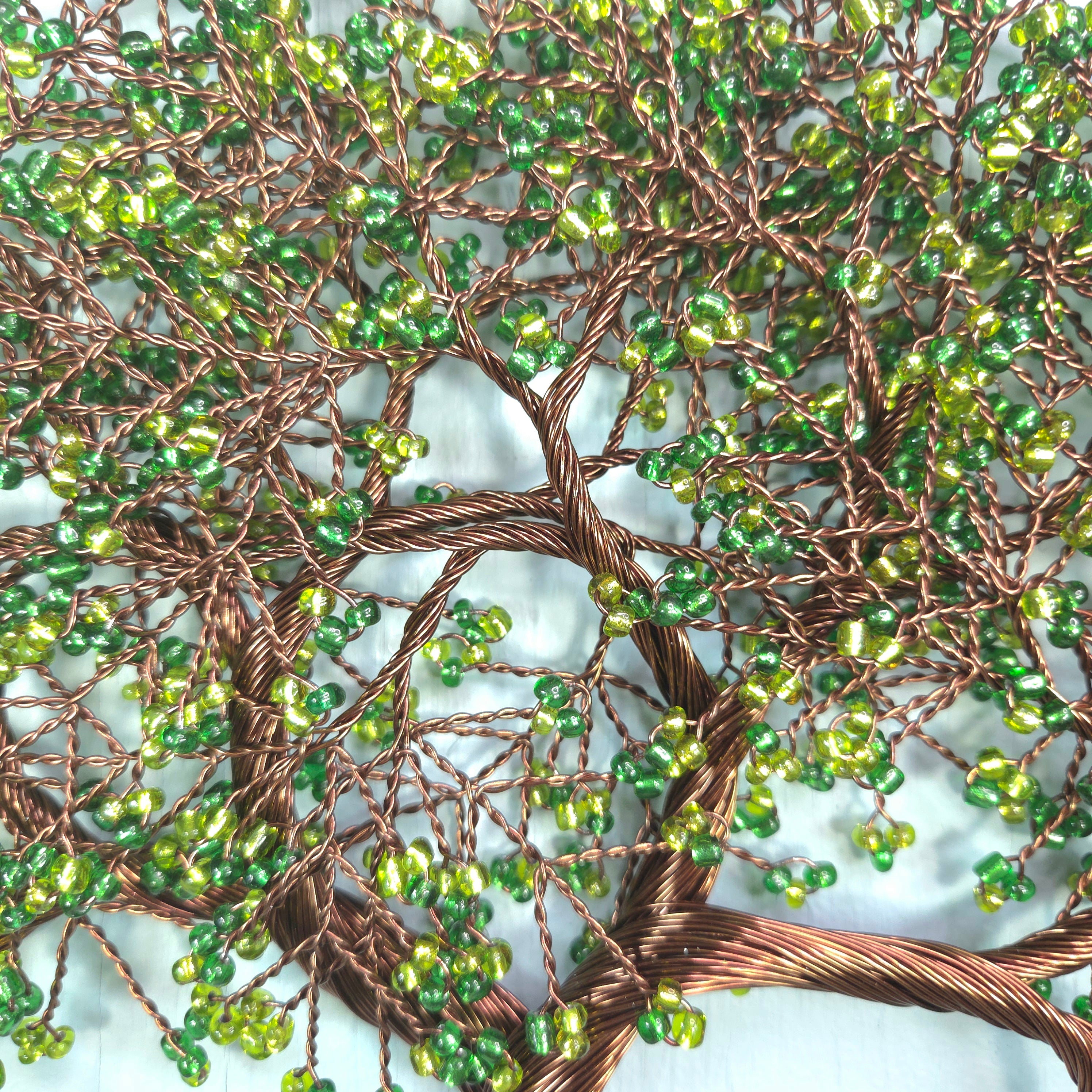 Close-up of a beaded tree artwork with green beads and brown wire branches.