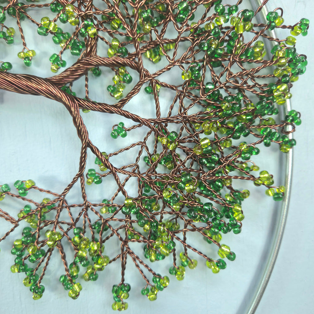 Decorative wall art with green beads and brown wire on a light blue background
