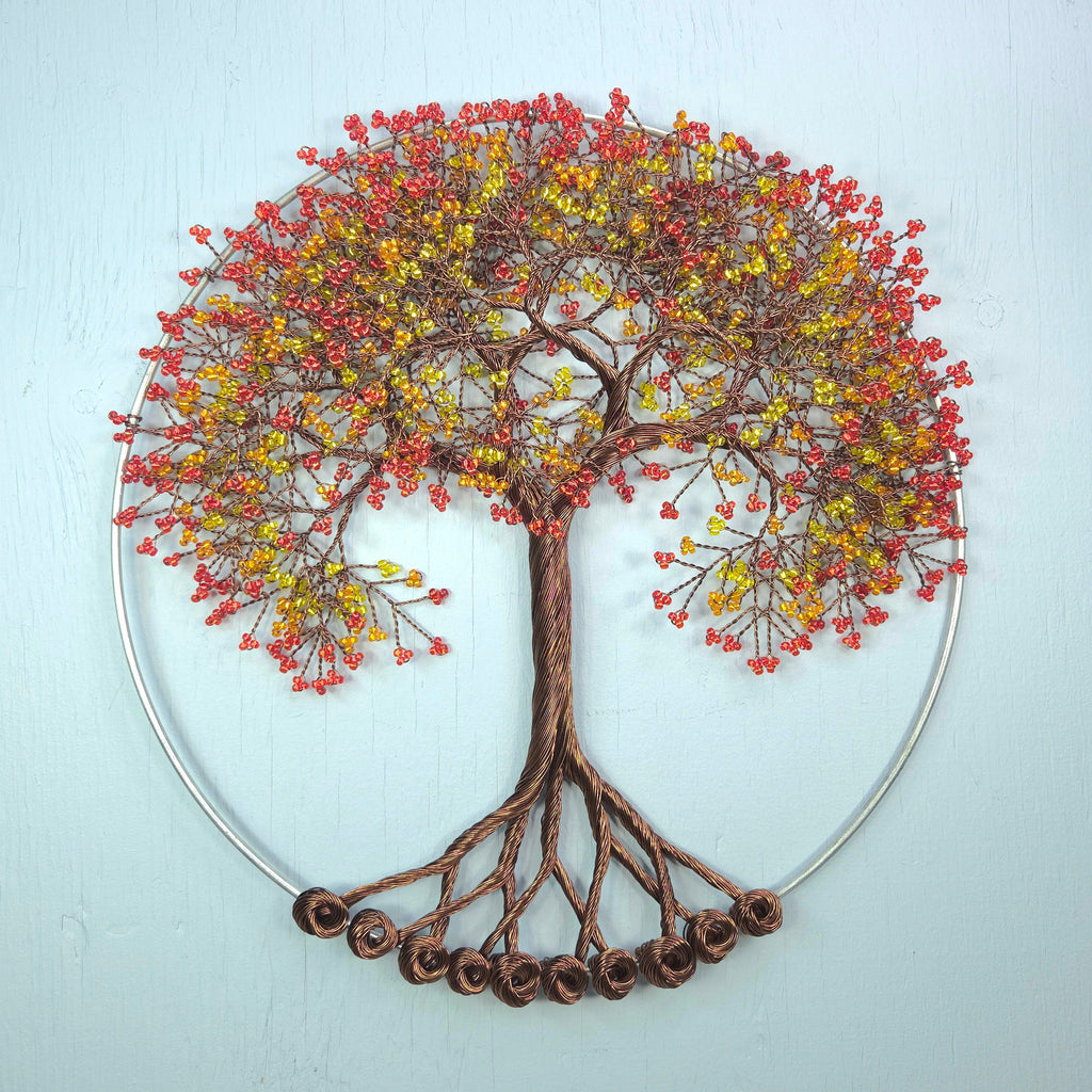 Decorative wall art of a tree with autumn foliage on a light blue background