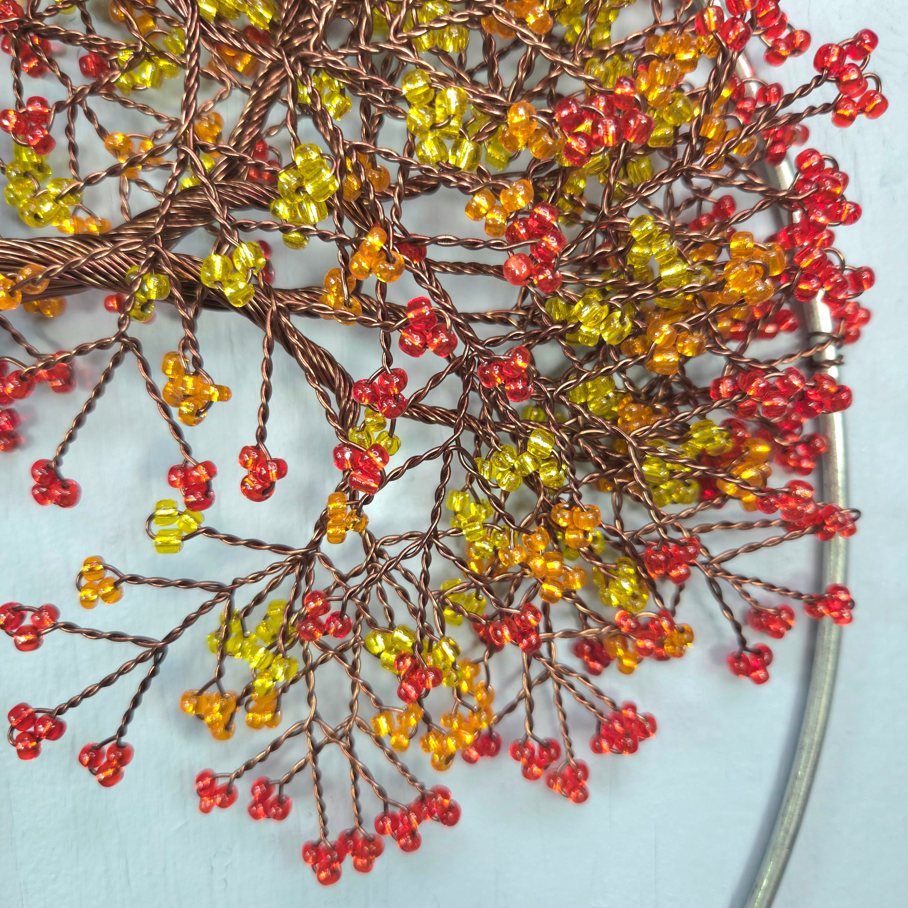 Decorative branch with red, yellow, and orange beads on a light blue background