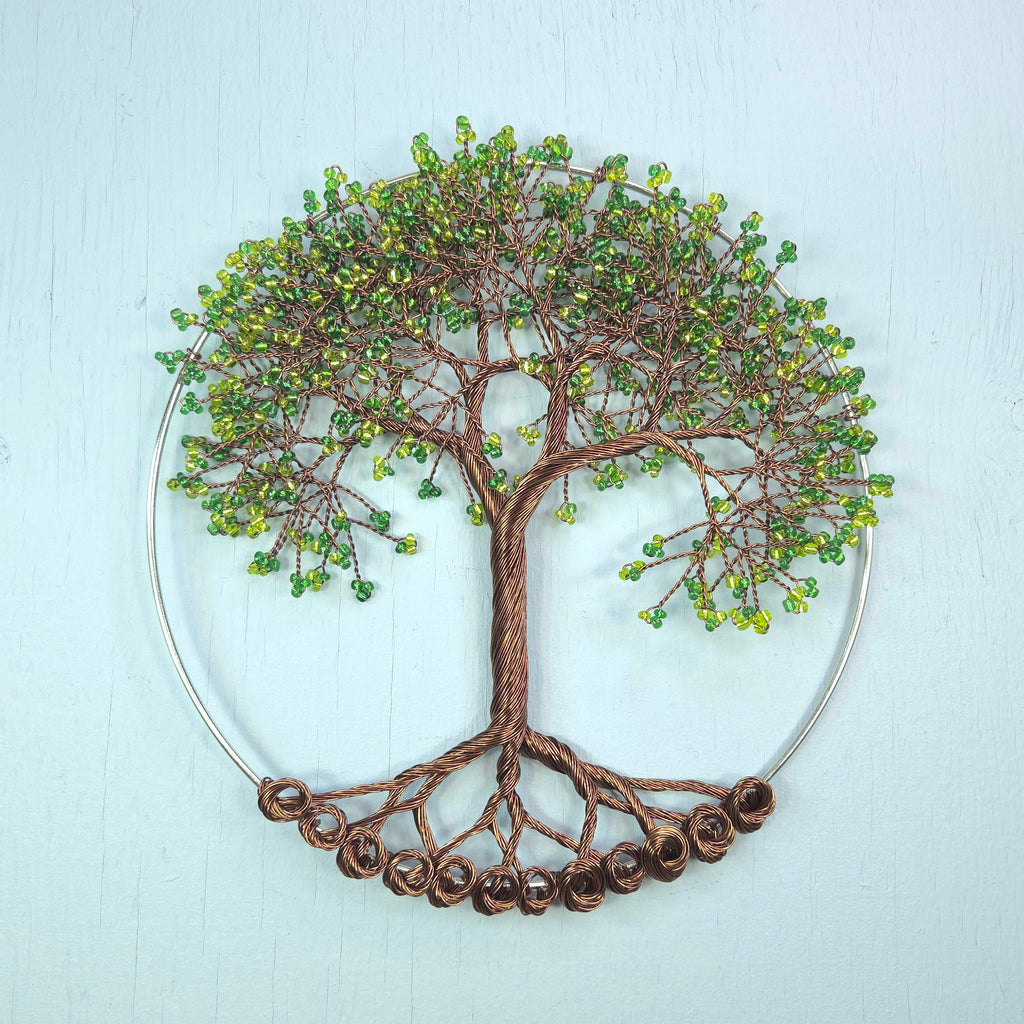 Decorative wall art of a tree with green beads on a light blue background