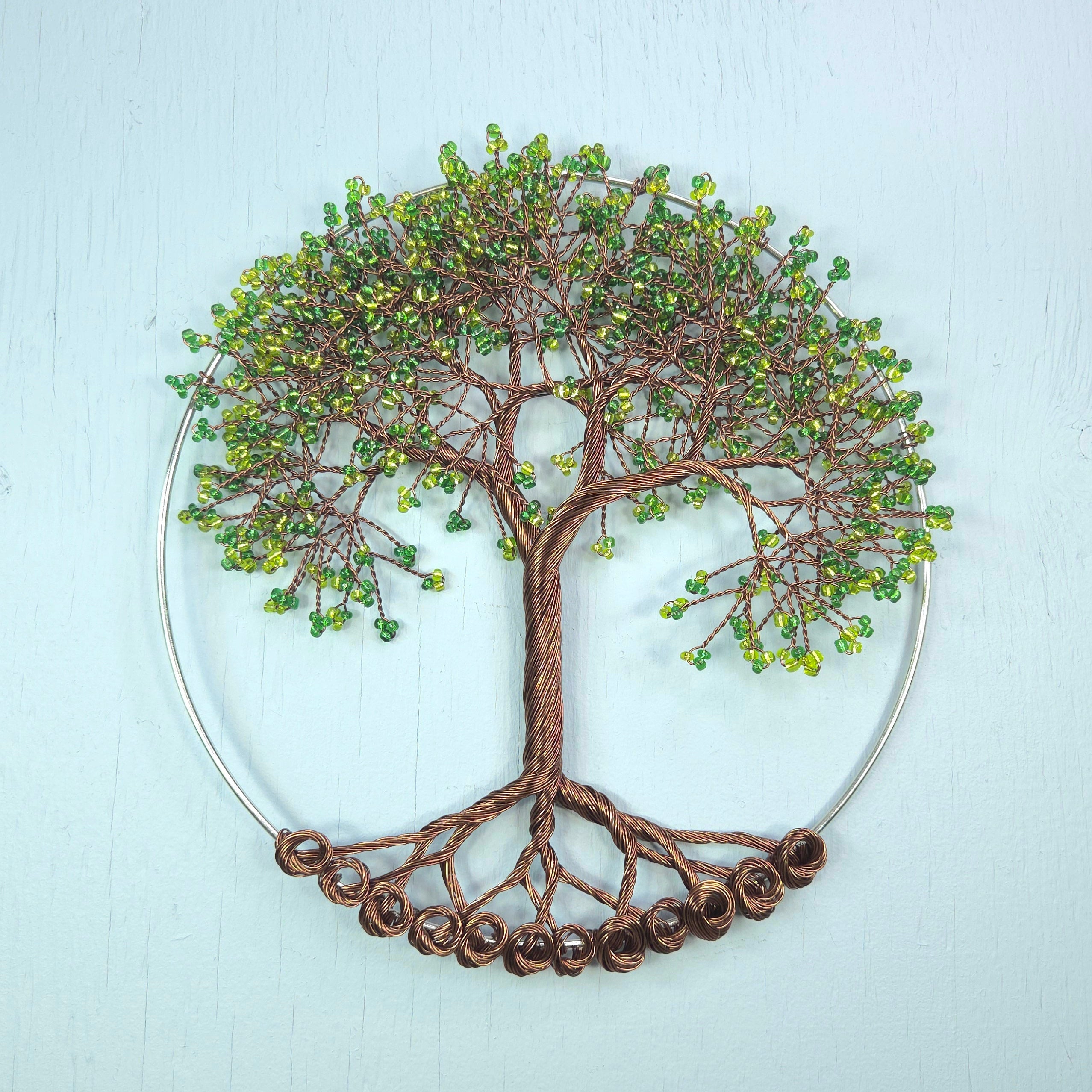 Decorative wall art of a tree with green beads on a light blue background