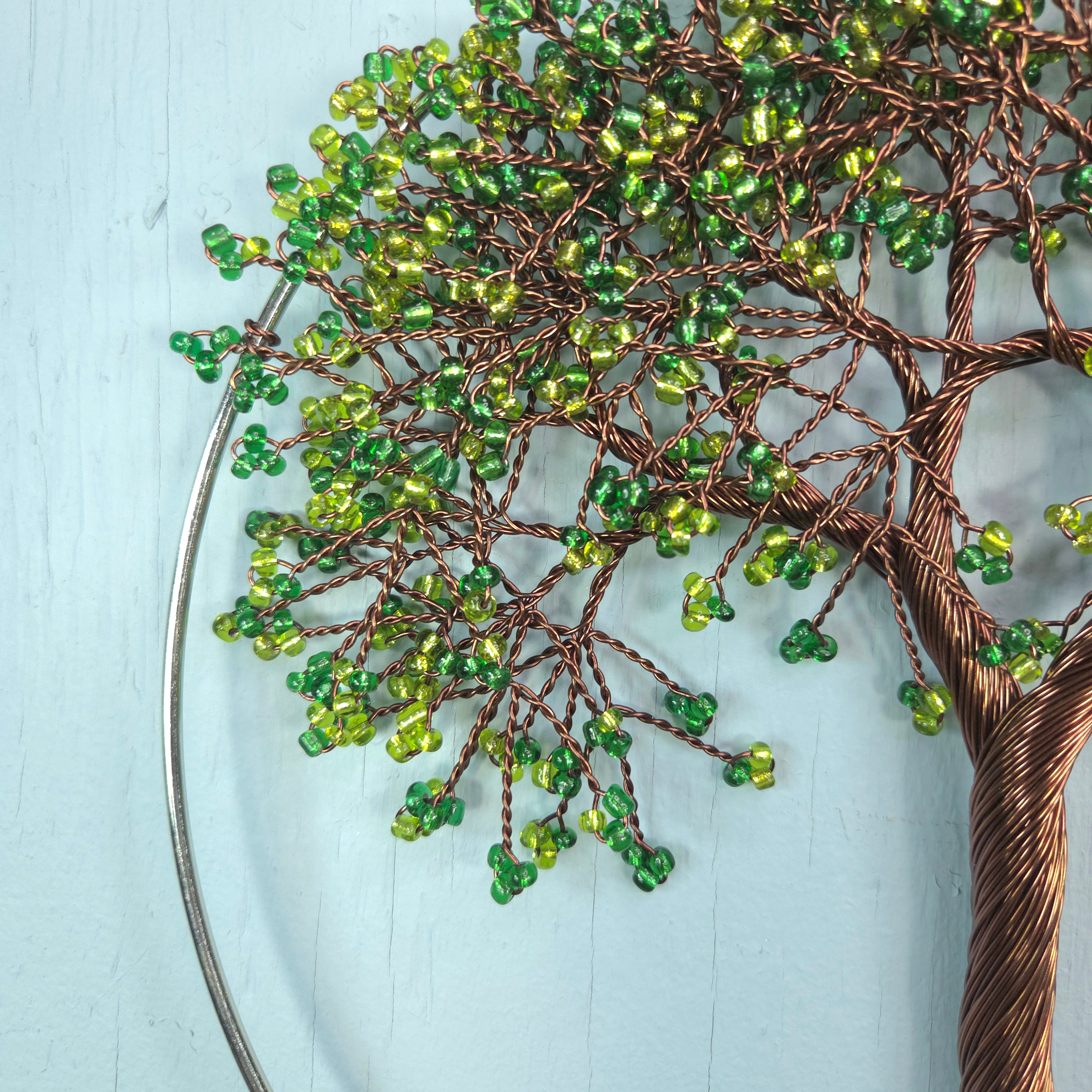 Decorative wall art of a tree with green beads on a light blue background