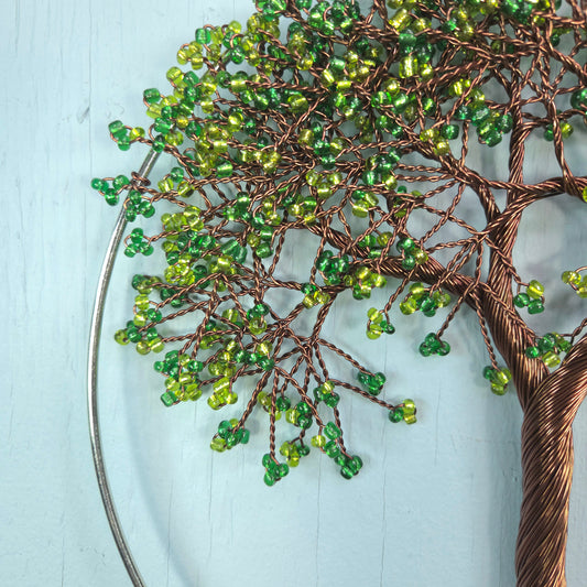 Decorative wall art of a tree with green beads on a light blue background