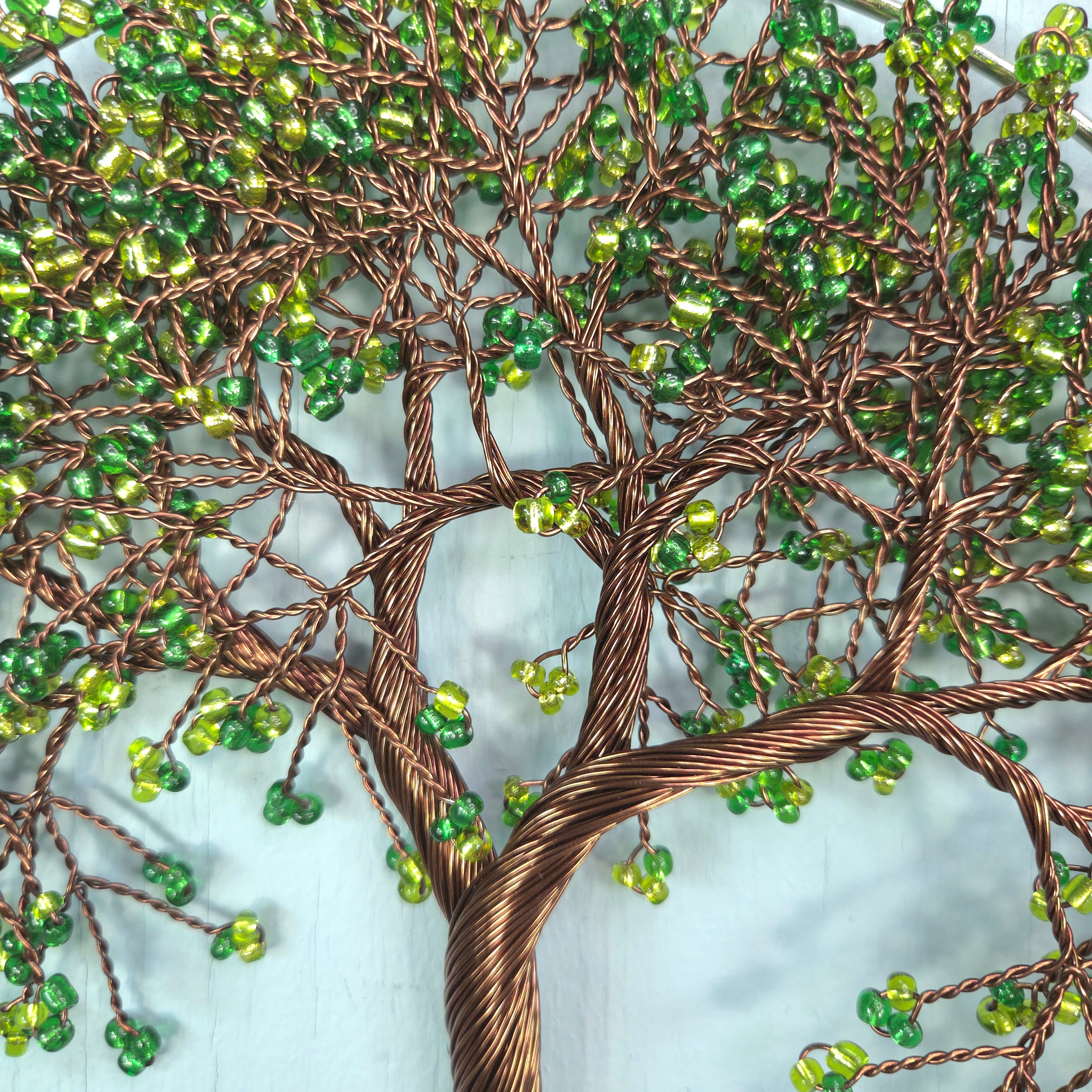 Decorative wall art of a tree with green beads on a light blue background