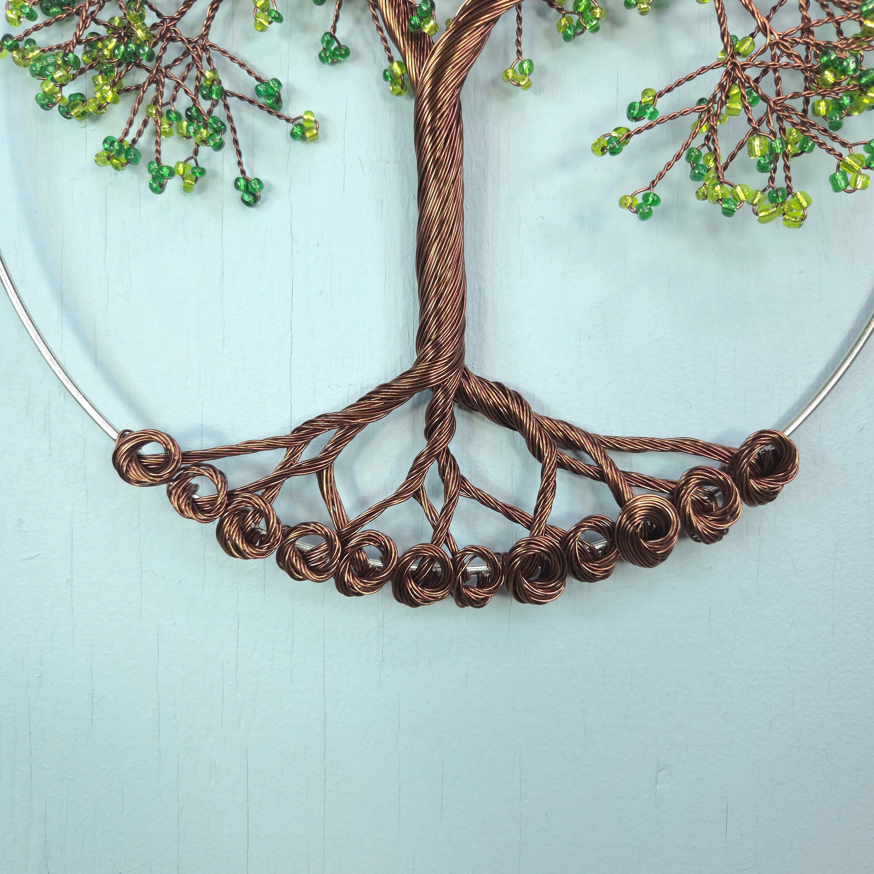 Decorative wall art of a tree with green beads on a light blue background