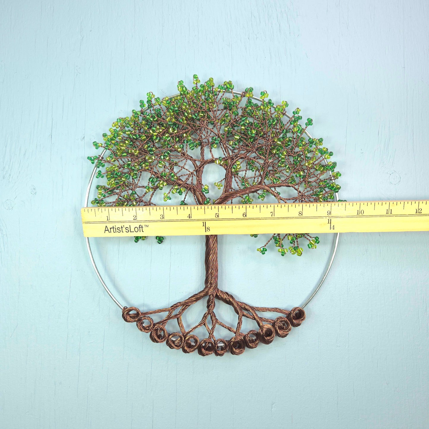 Decorative tree wall art with a ruler for scale on a light blue background