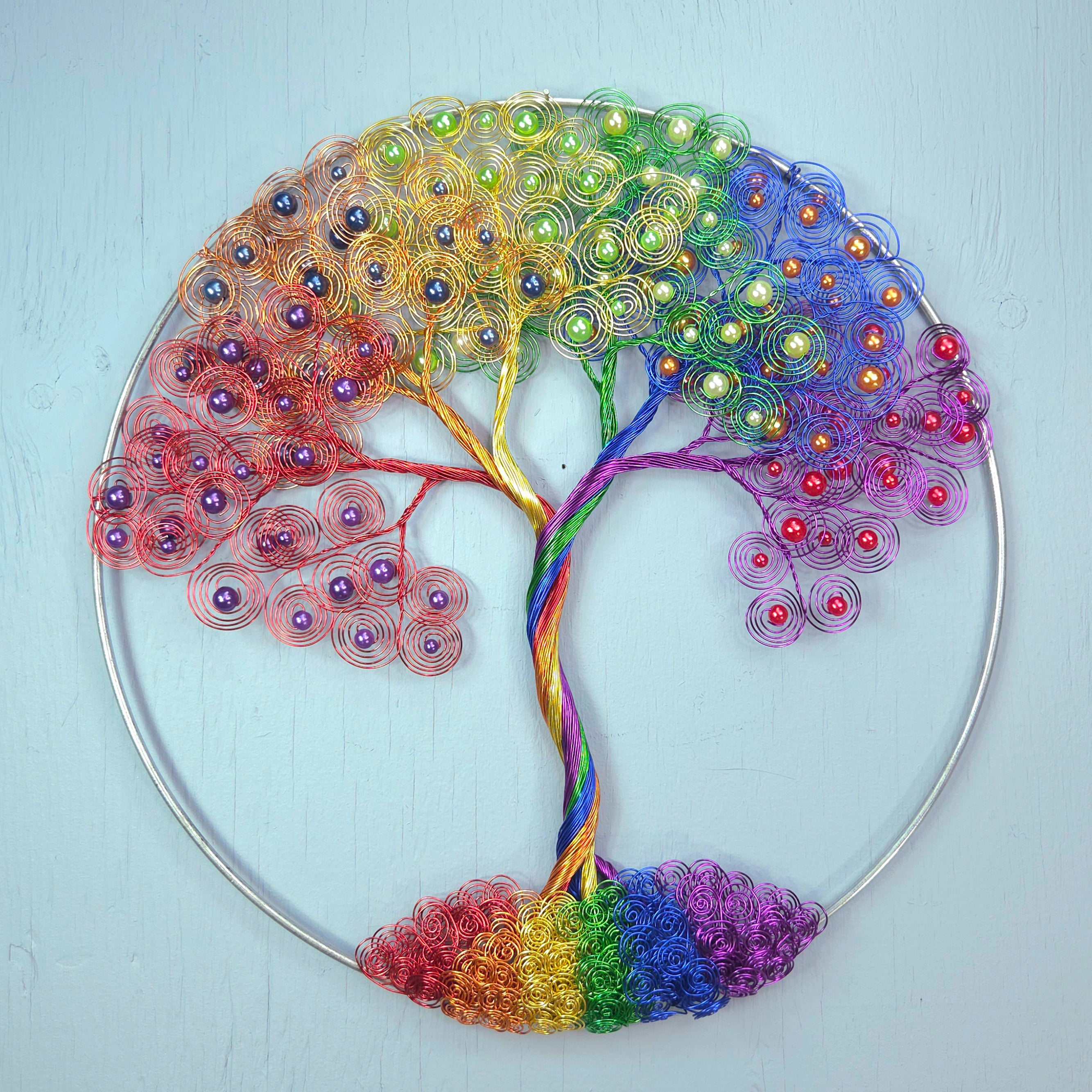 Colorful tree-shaped decorative item with beads on a light blue background
