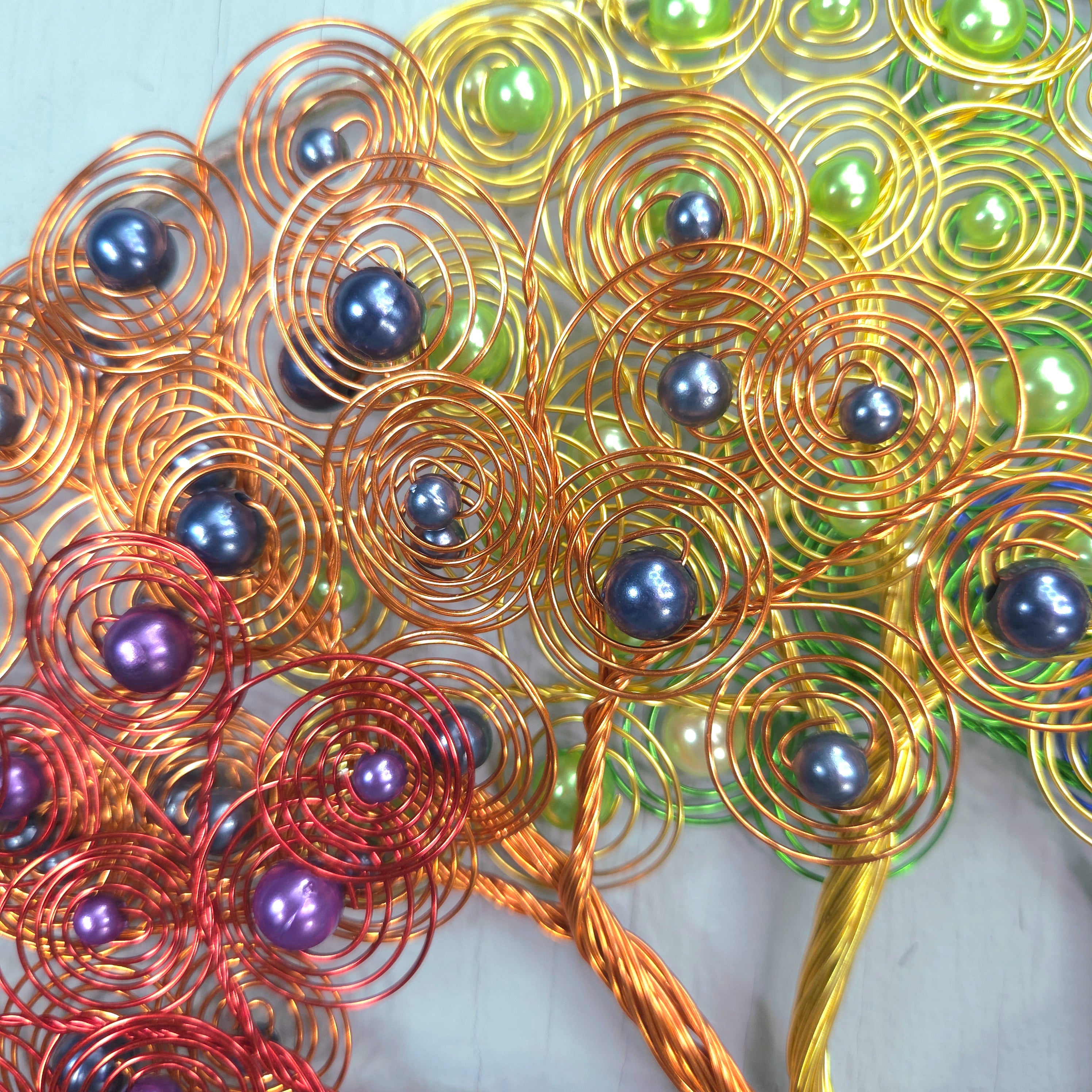 Decorative wall art with interwoven metal wires and beads on a light background