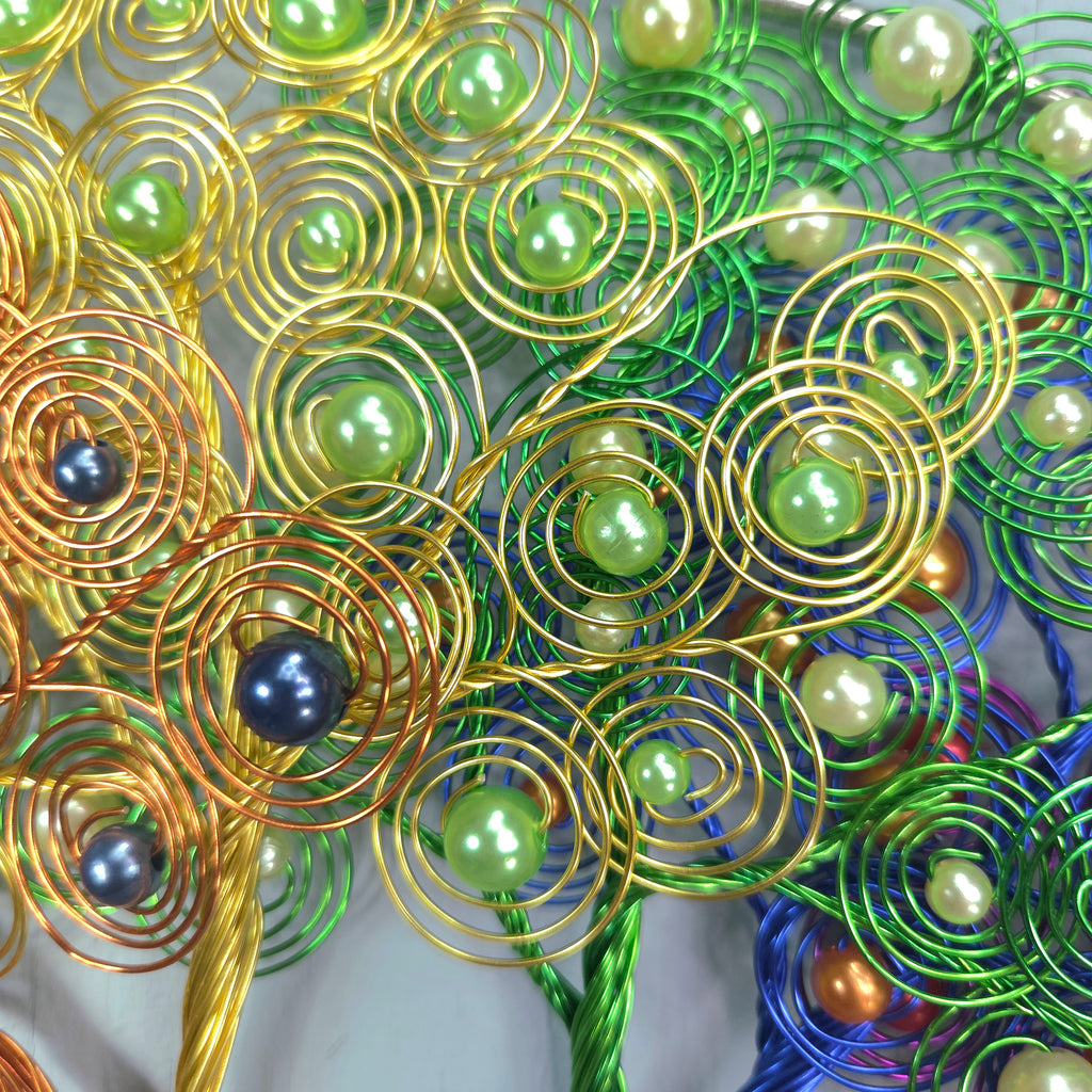 Decorative wreath with gold, green, and blue wire and beads on a white background