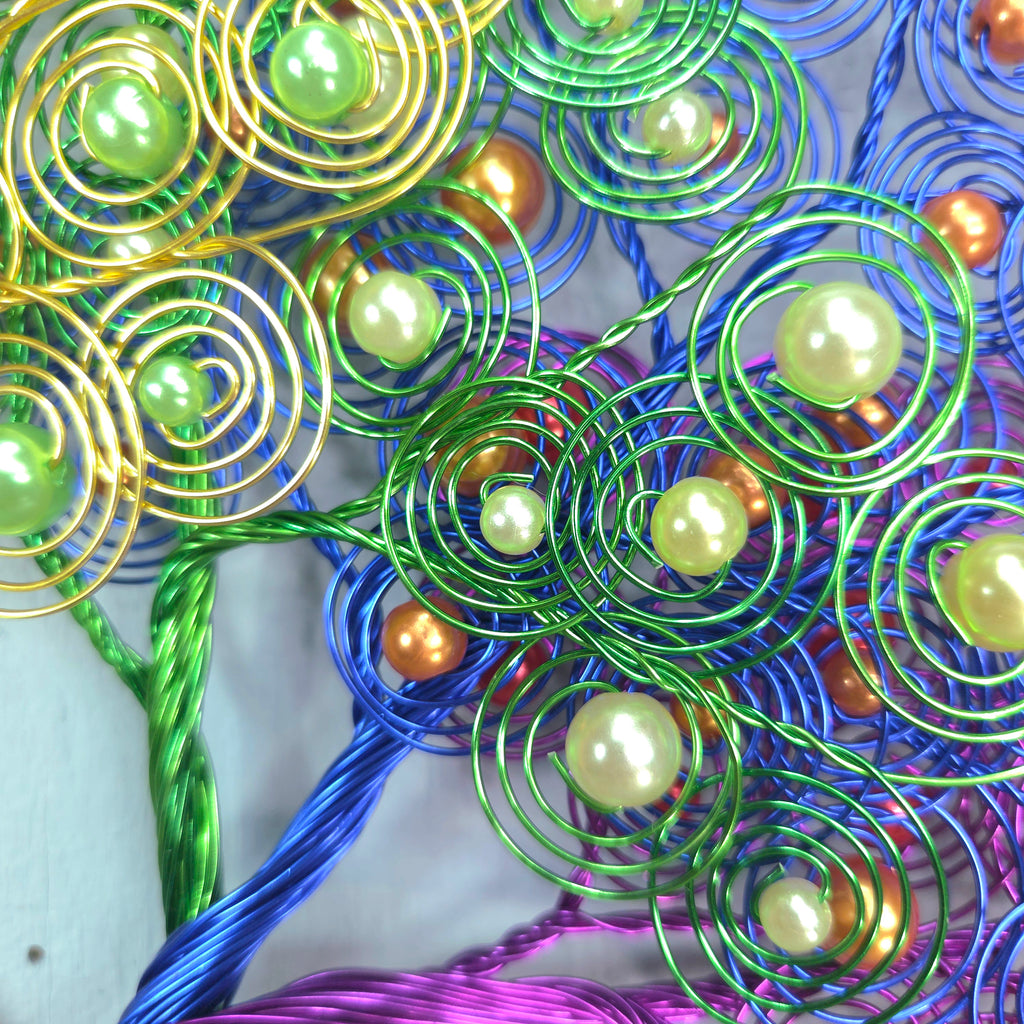 Colorful wire tree sculpture with beads on a white background