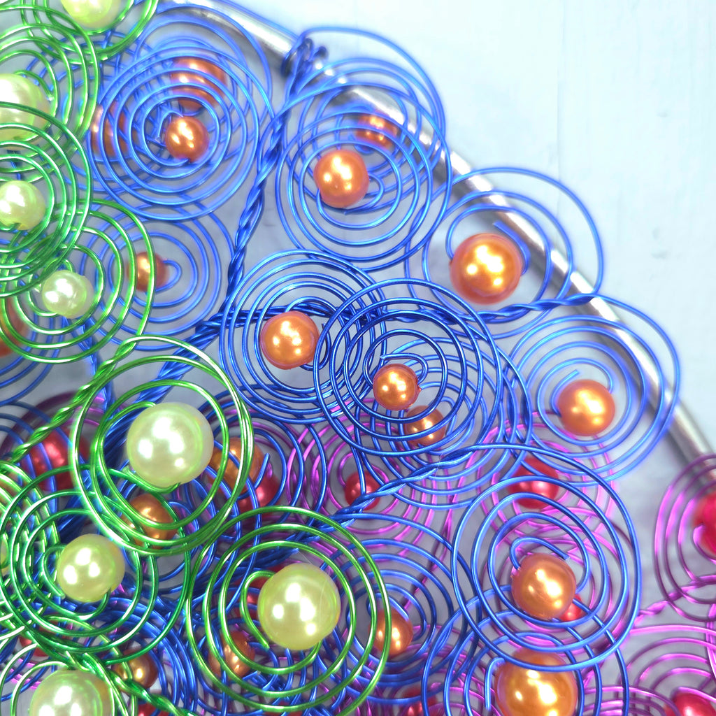 Colorful metal spiral beads with pearls on a white background