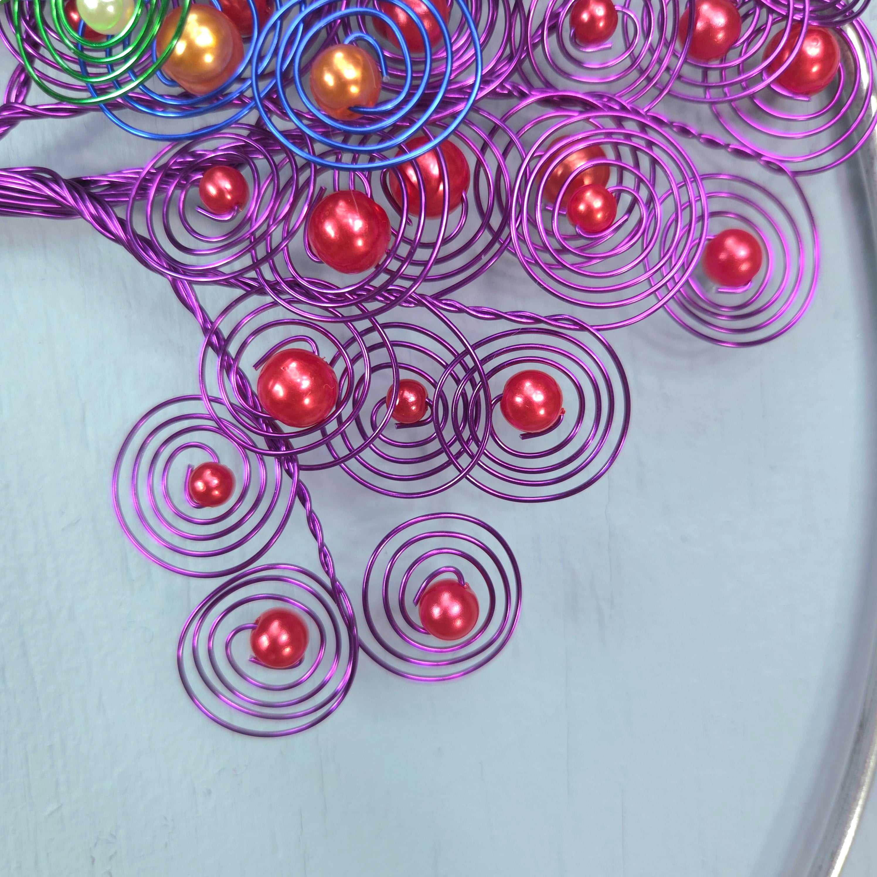 Purple wire spirals with red beads on a light gray background