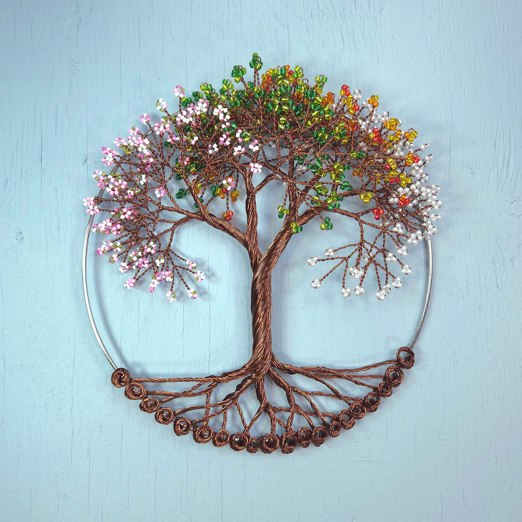 Decorative wall art of a tree with colorful leaves on a light blue background