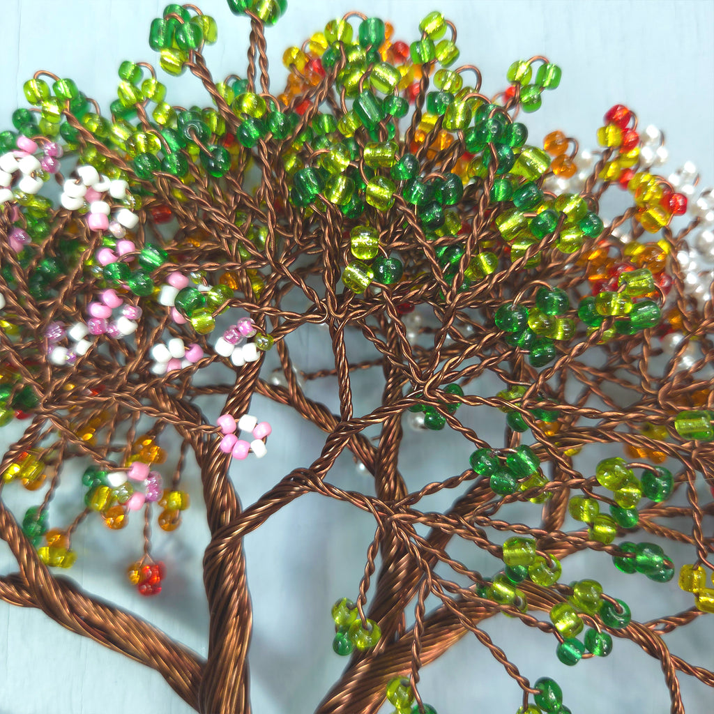 Decorative tree made of wire and beads on a light blue background
