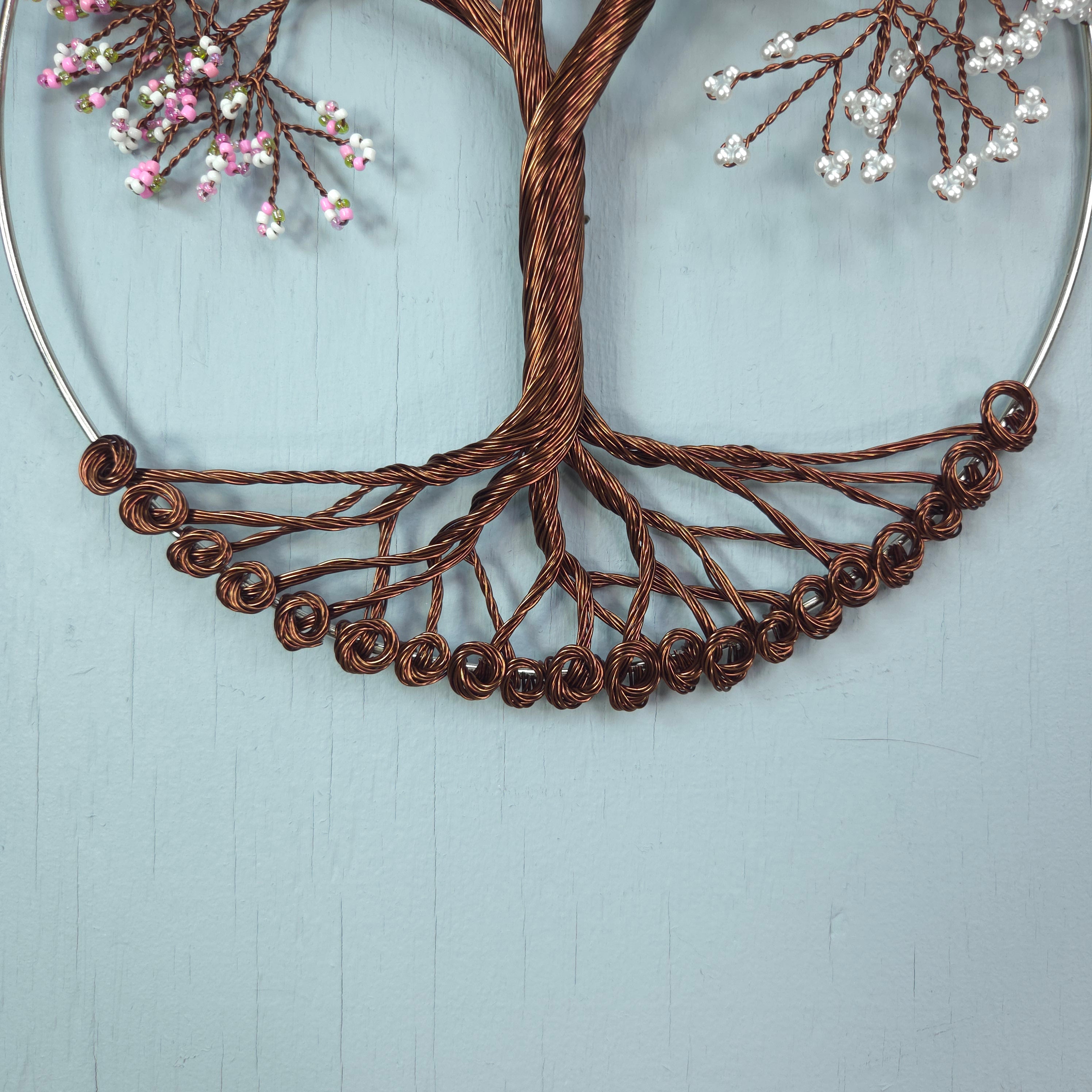 Decorative wreath with brown wire design and small flowers on a light blue background