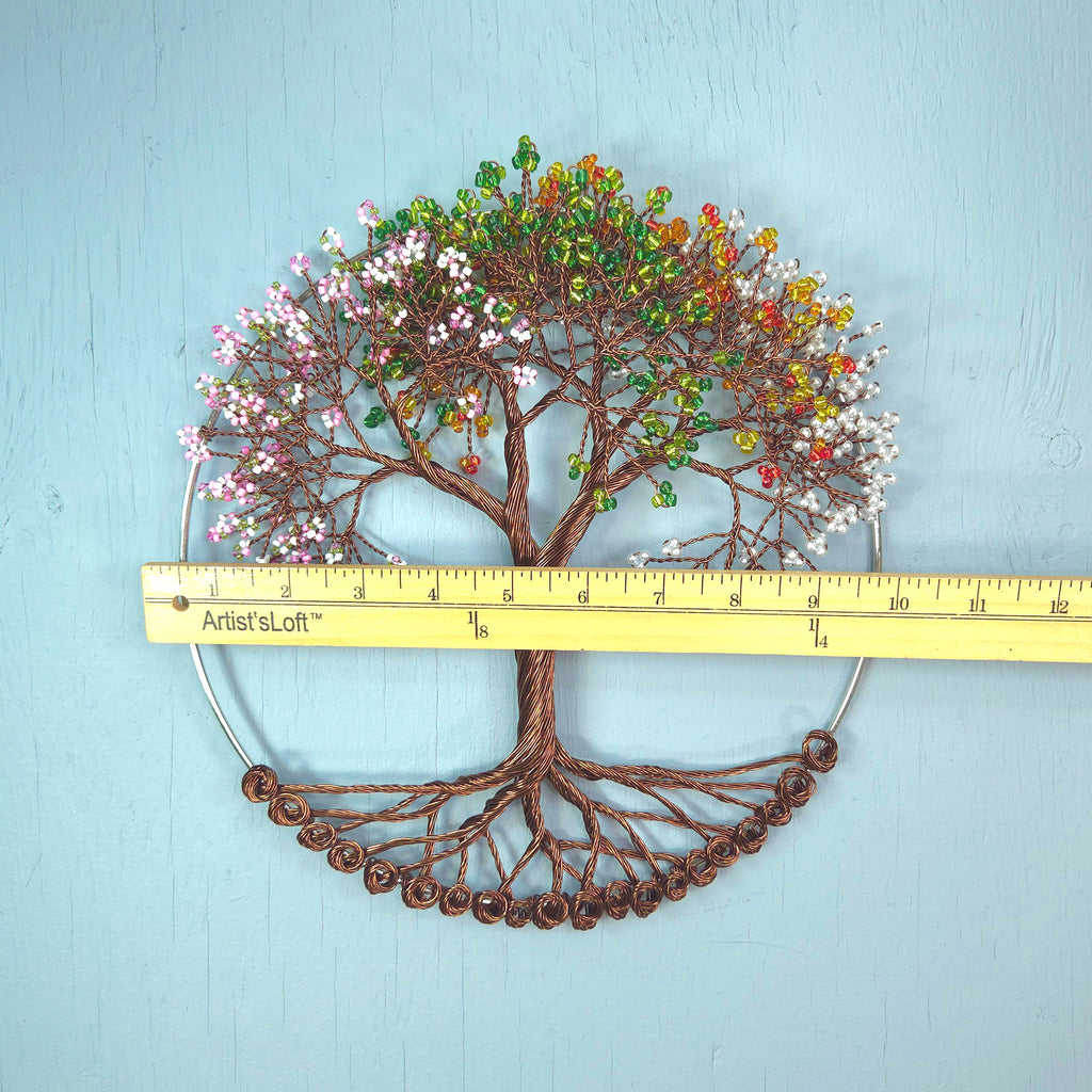 Decorative tree wall art with colorful leaves and a ruler for scale on a light blue background