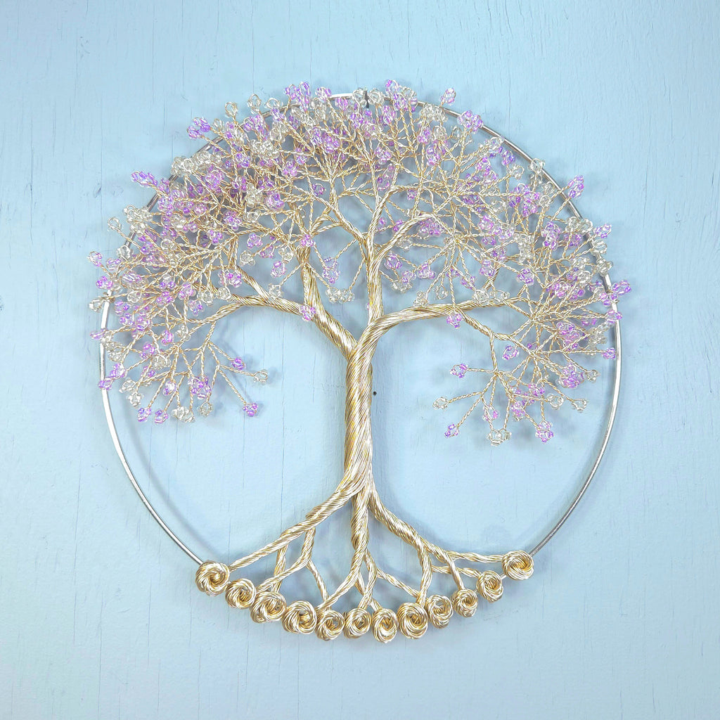 Decorative metal tree wall art with purple flowers on a light blue background